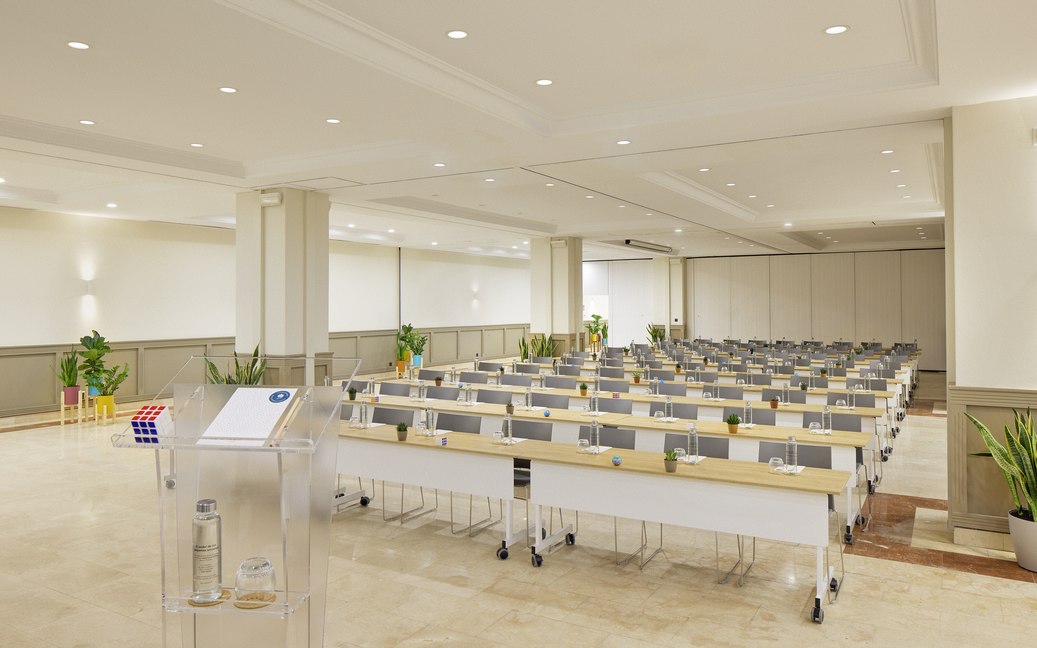 Modern conference room with rows of tables, chairs, and a clear lectern.