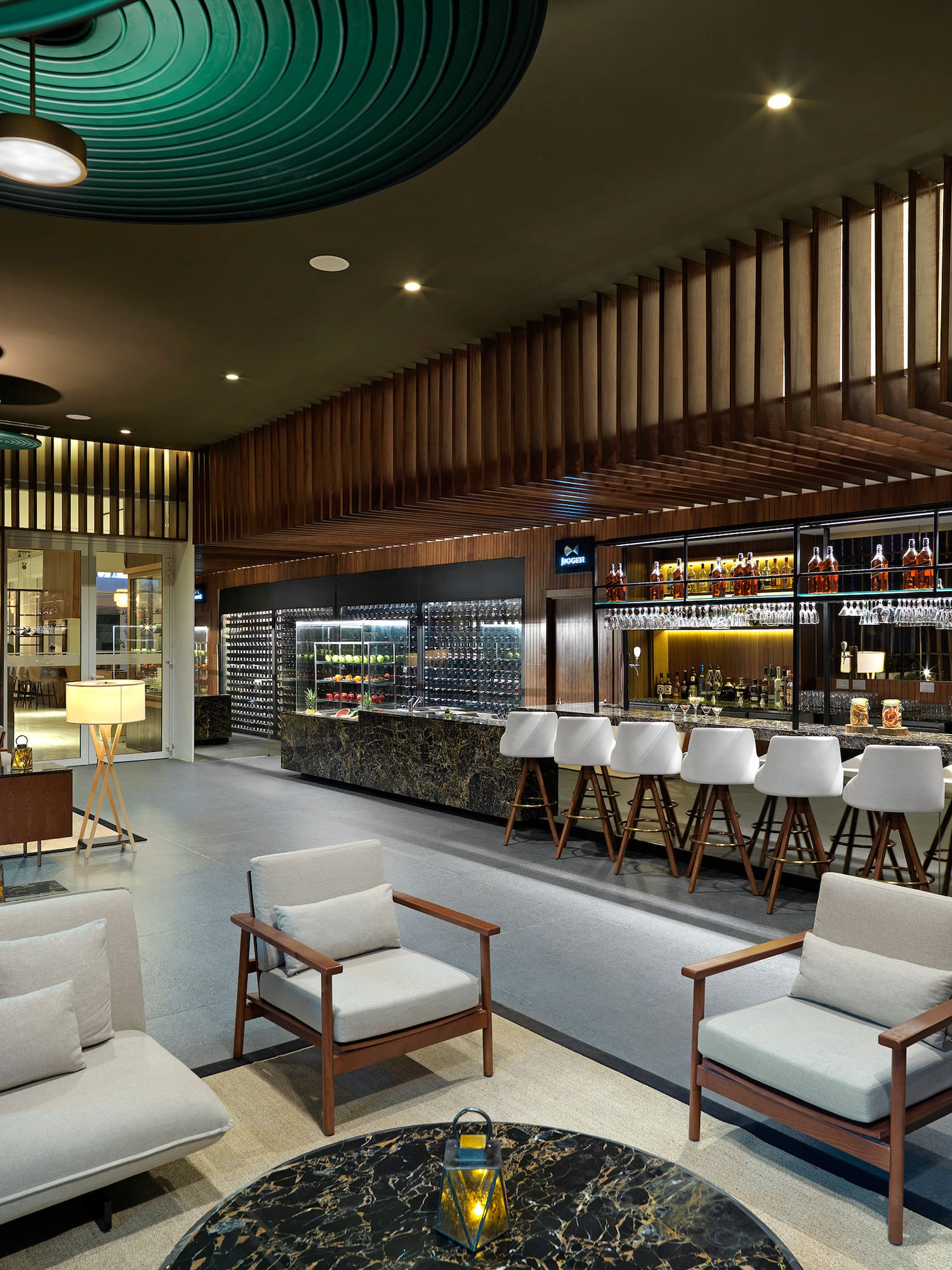 Modern hotel lounge bar with seating and wine display.