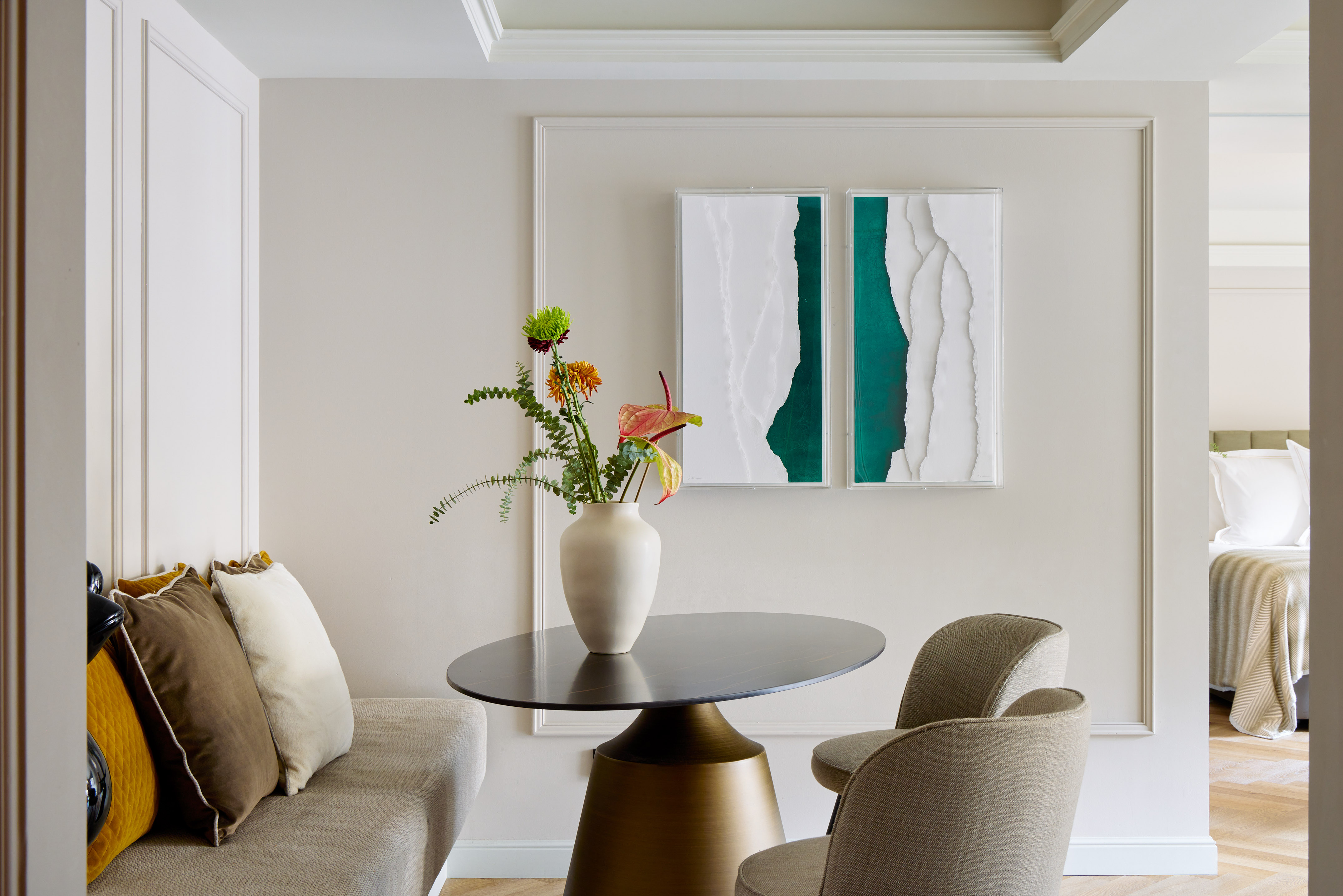 Luxurious hotel suite dining area with modern abstract art, round table, and flowers.