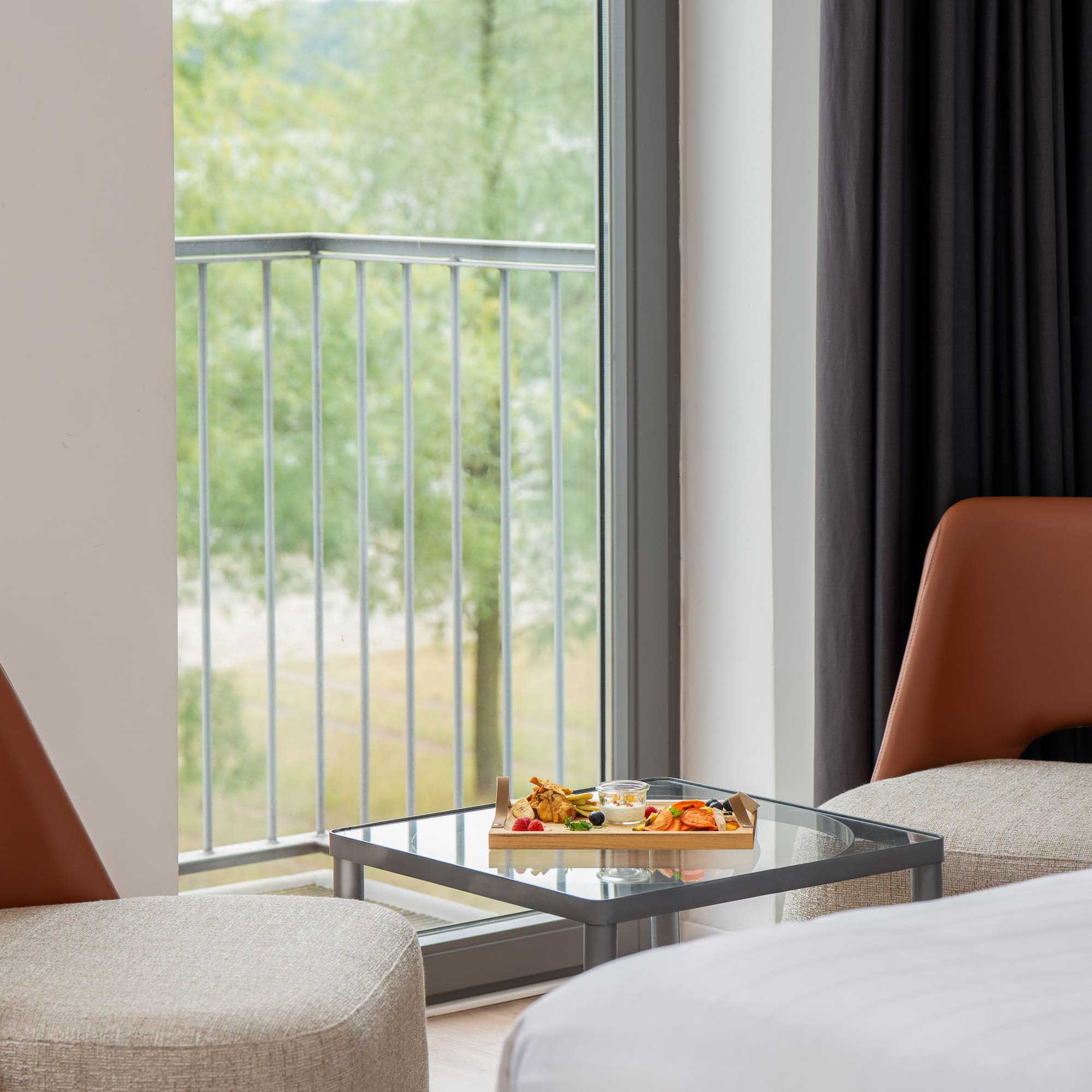 a tray of food on a glass table next to a bed and chairs