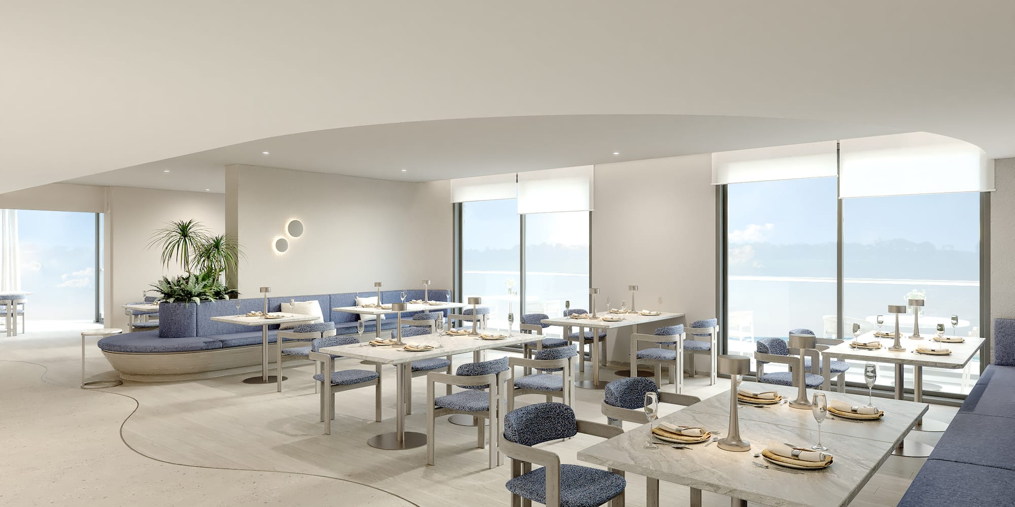 Contemporary restaurant with blue seating, marble tables, and ocean view.