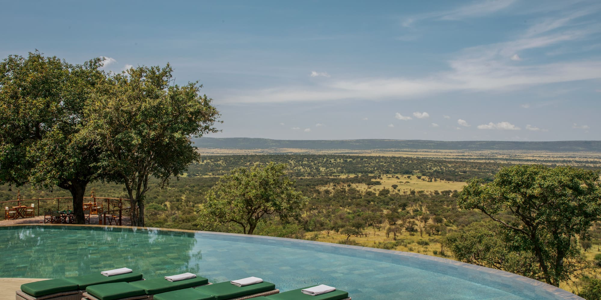 a pool with lounge chairs and trees in the background