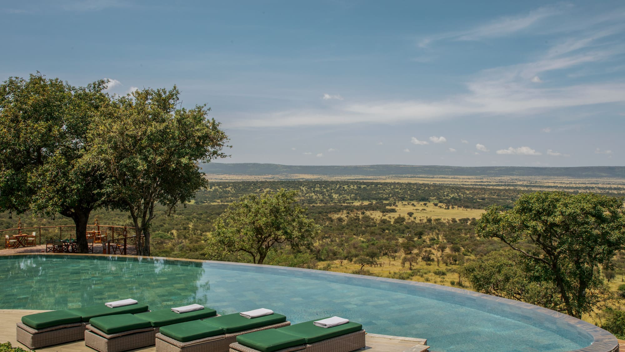 a pool with lounge chairs and trees in the background