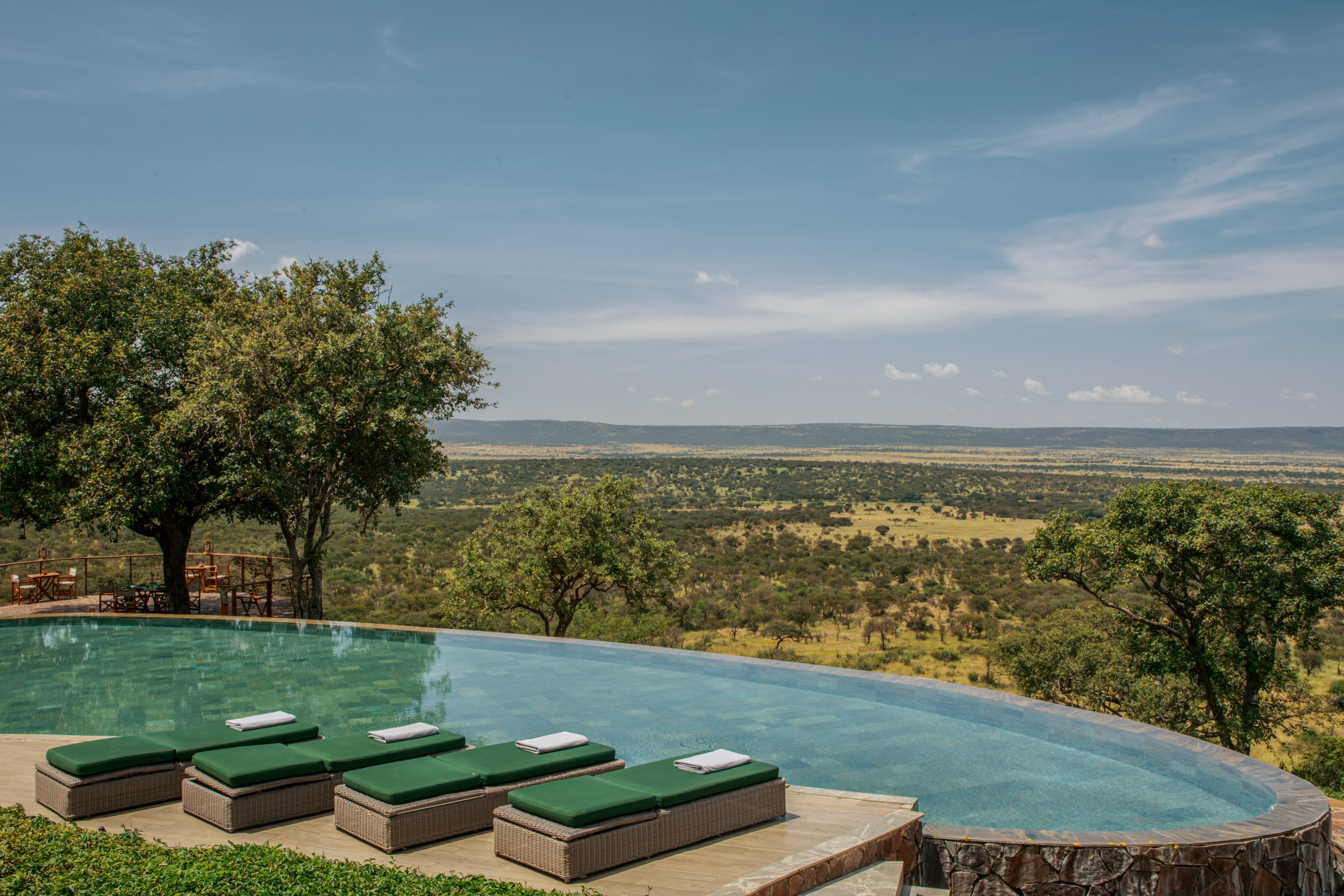 Outdoor infinity pool with sun loungers, panoramic savanna view, Africa.