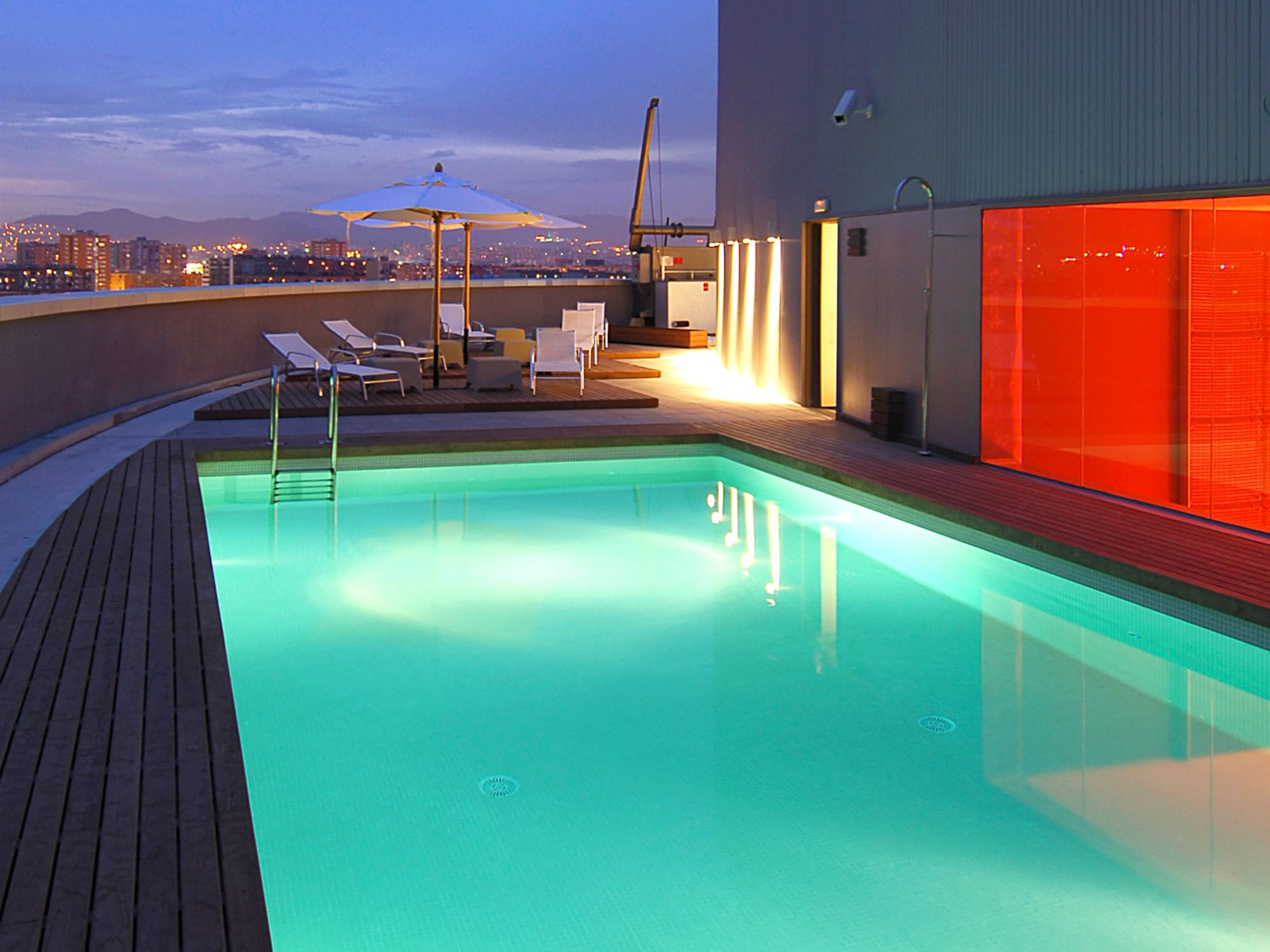 a pool with a deck and umbrella on a rooftop