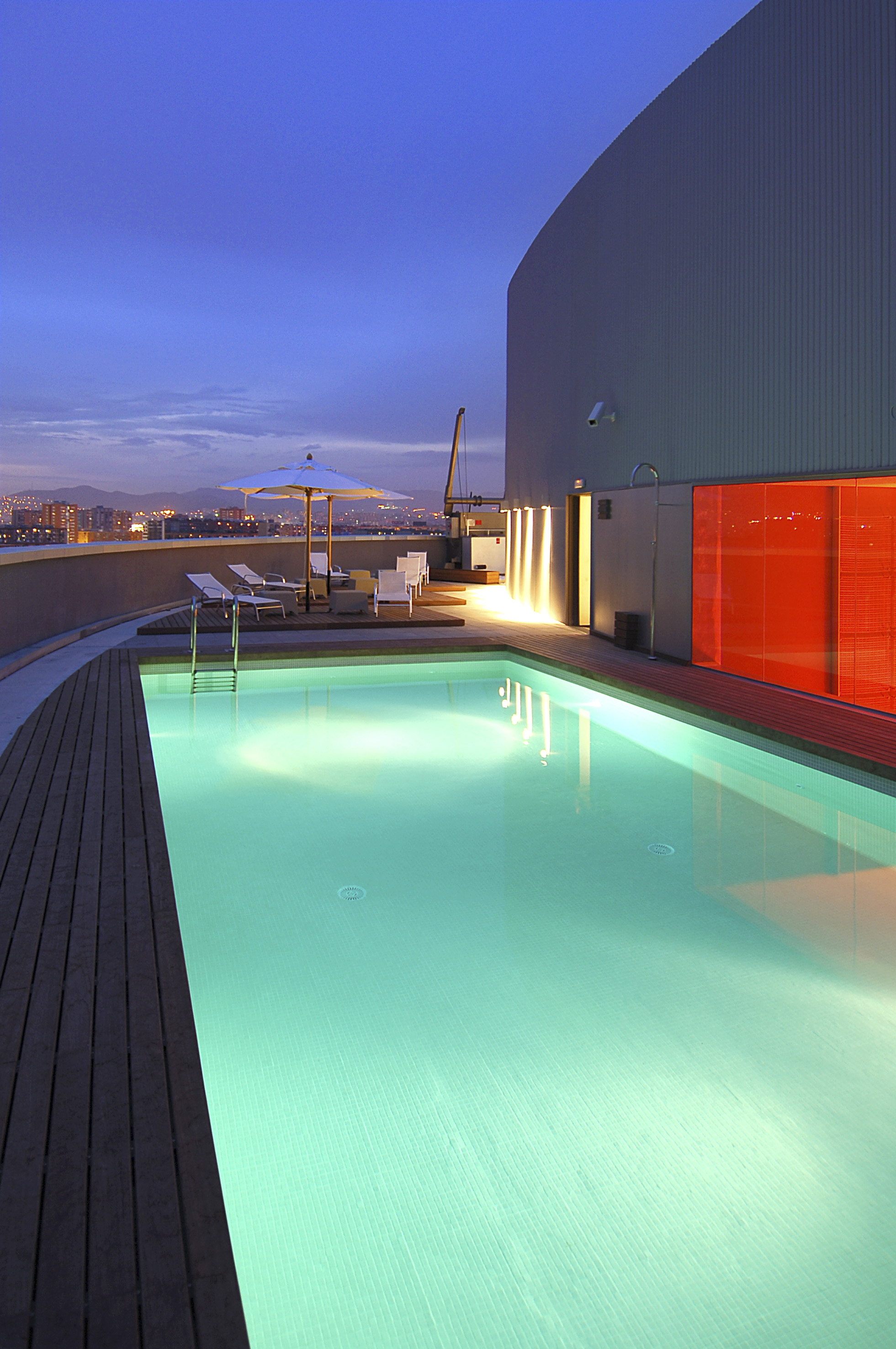 a pool with a deck and umbrella on a rooftop