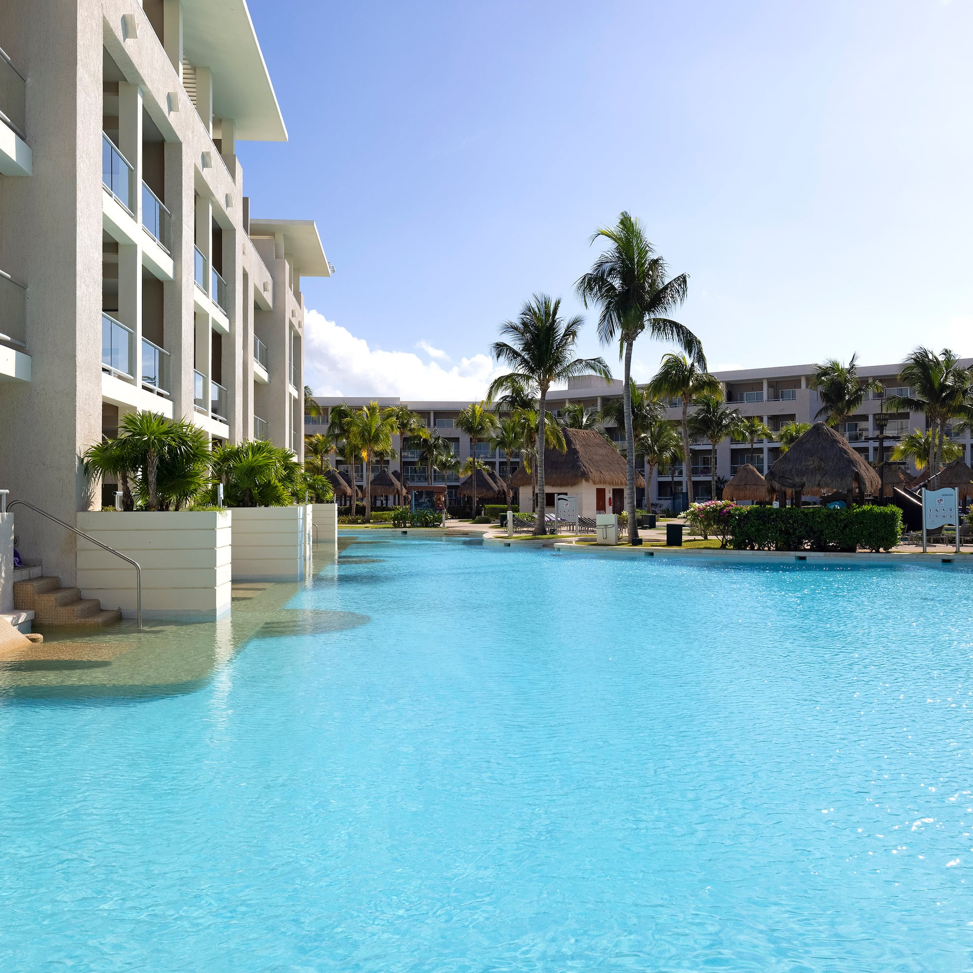 a pool with palm trees and buildings in the background
