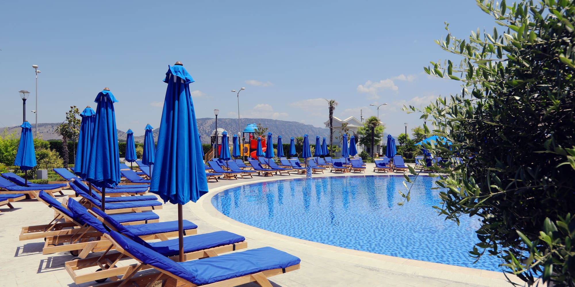 a pool with blue chairs and umbrellas