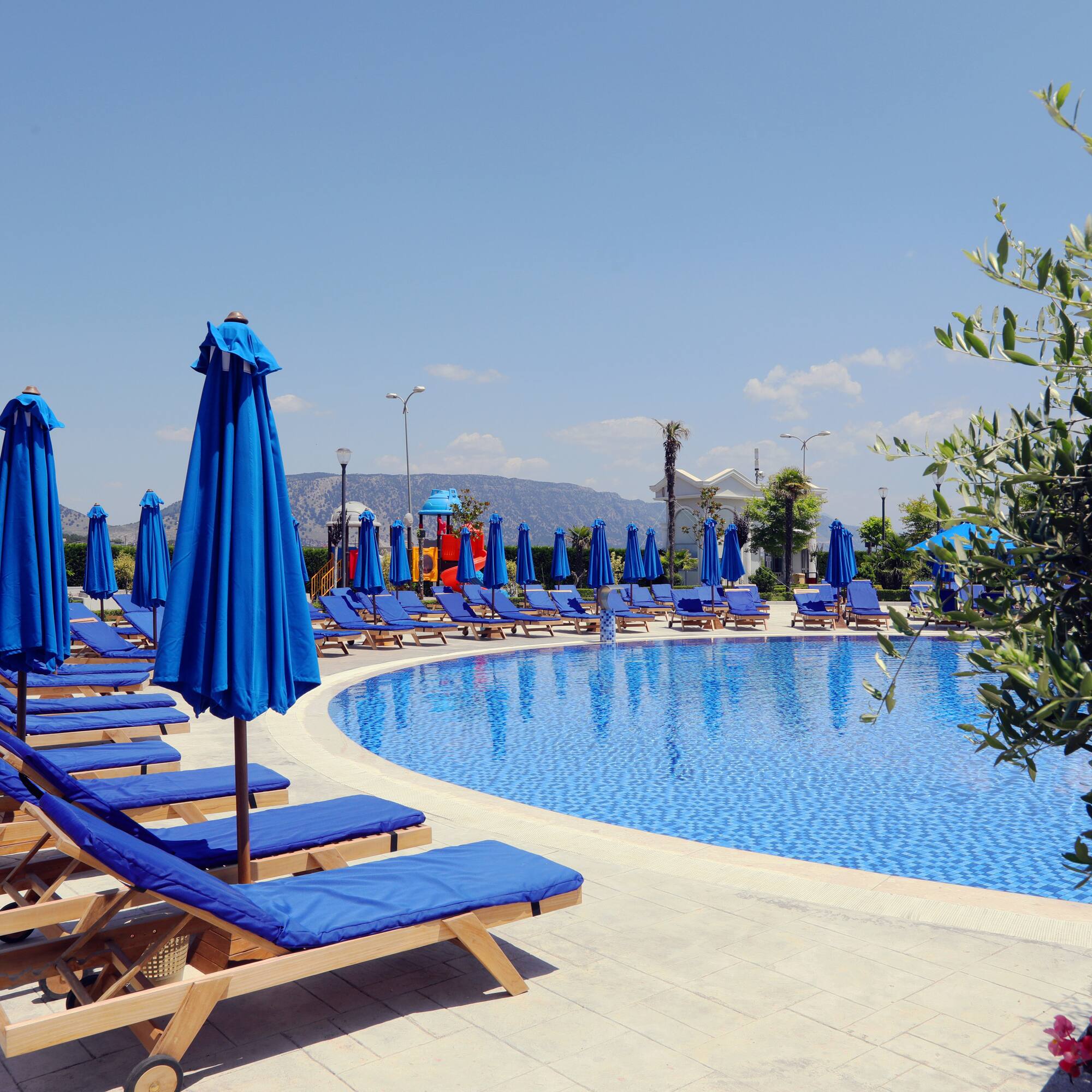 a pool with blue chairs and umbrellas