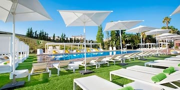 a pool with white umbrellas and lounge chairs