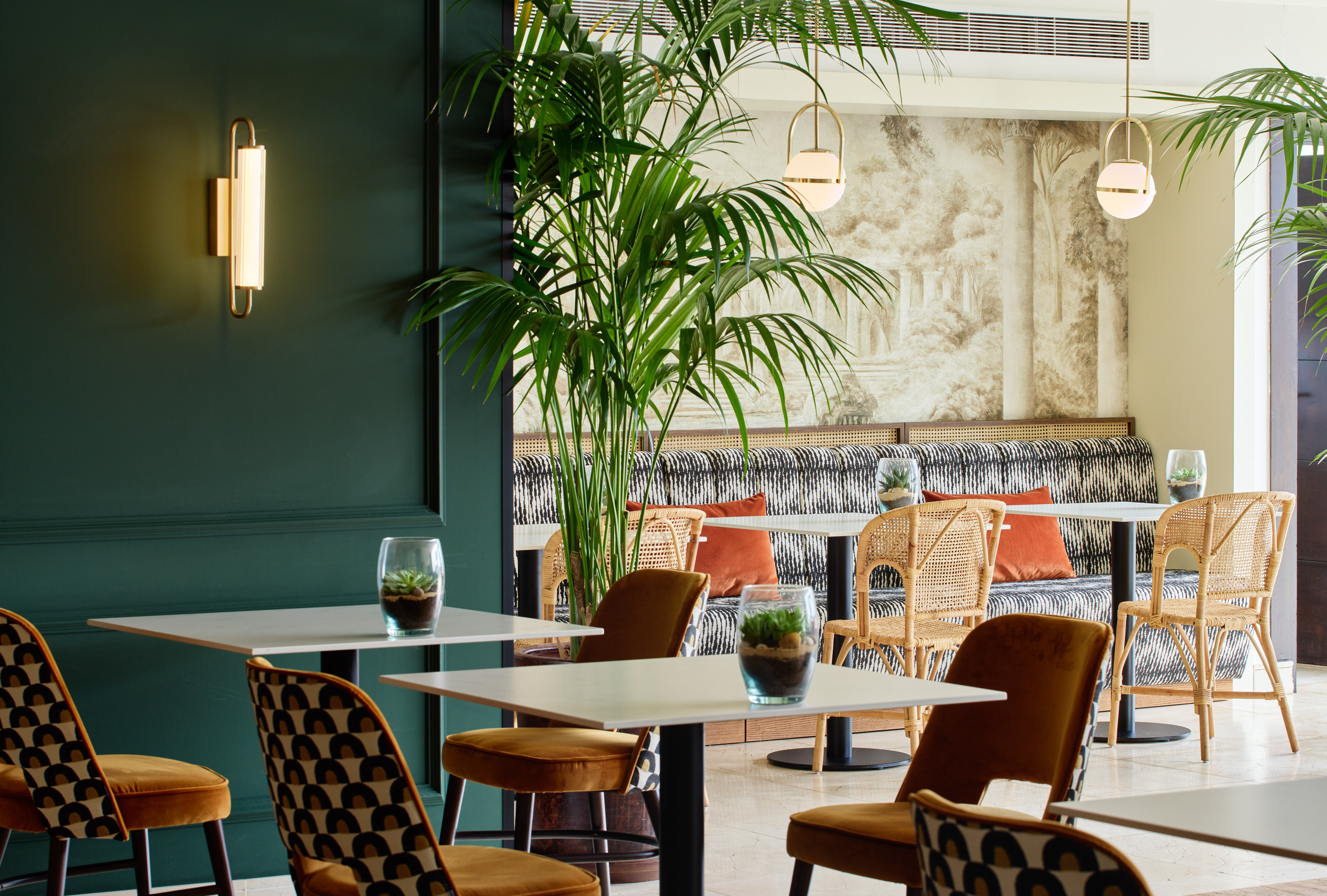 Botanical restaurant interior with green walls, palm trees, and modern seating.