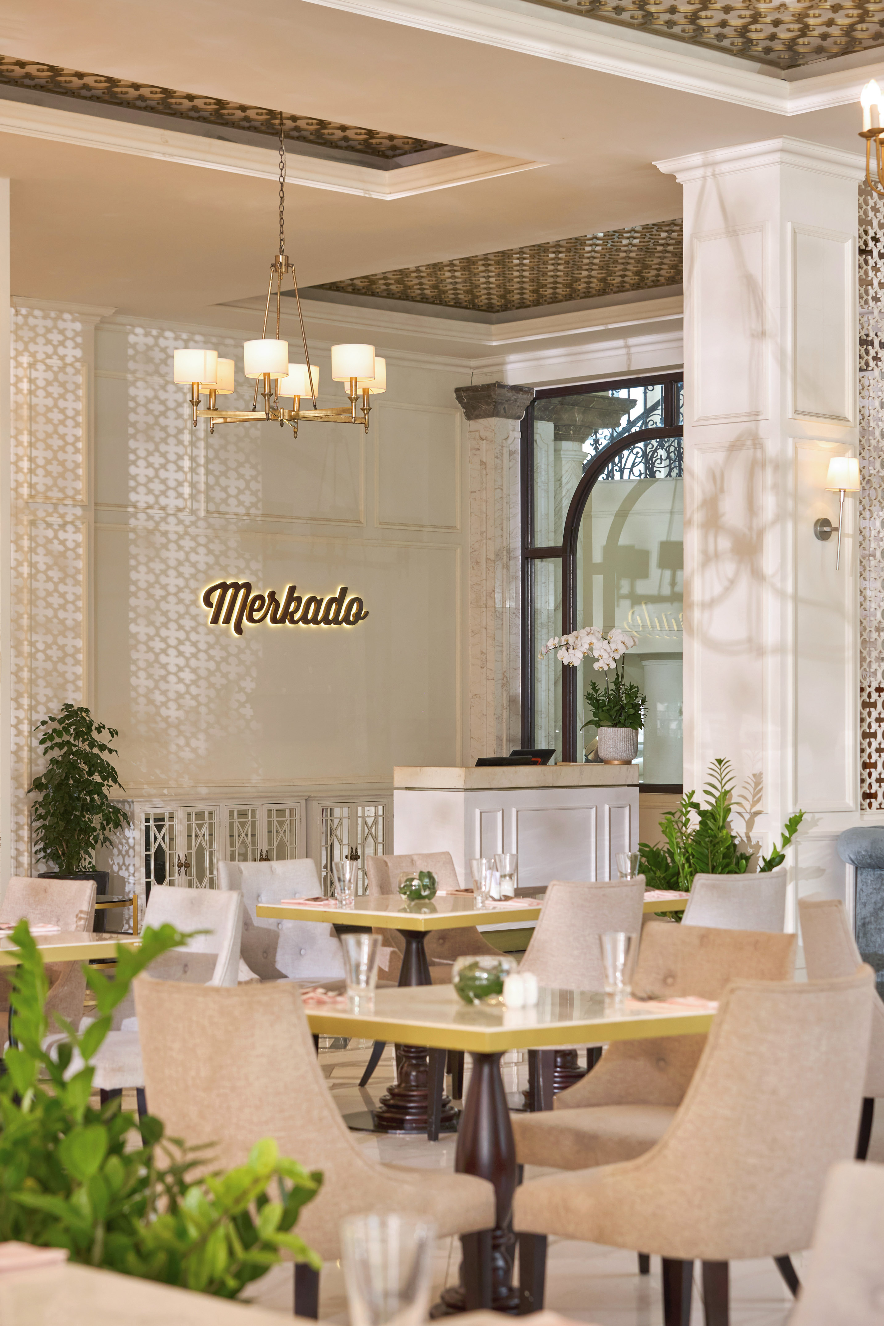 Elegant Merkado restaurant dining area with illuminated sign and chandelier.