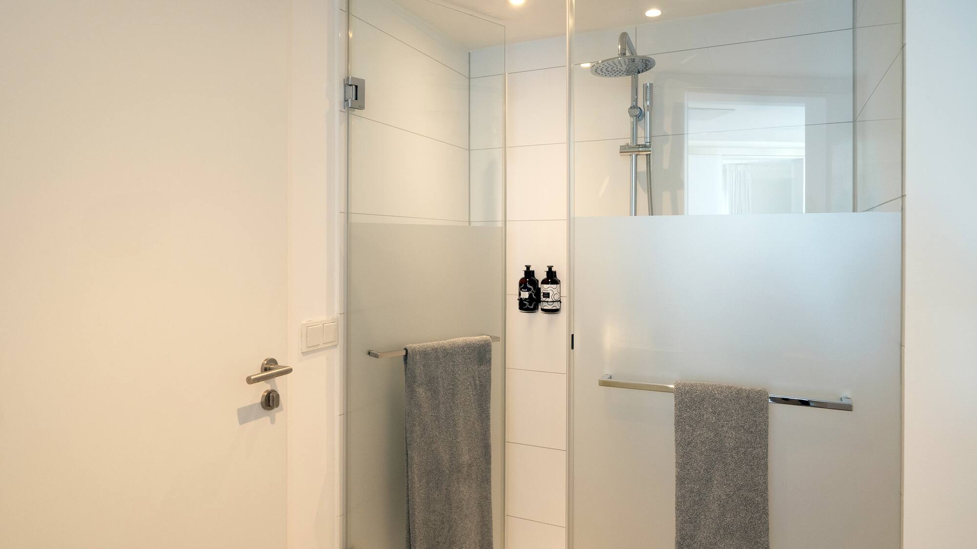 a shower with a glass door and a shower head