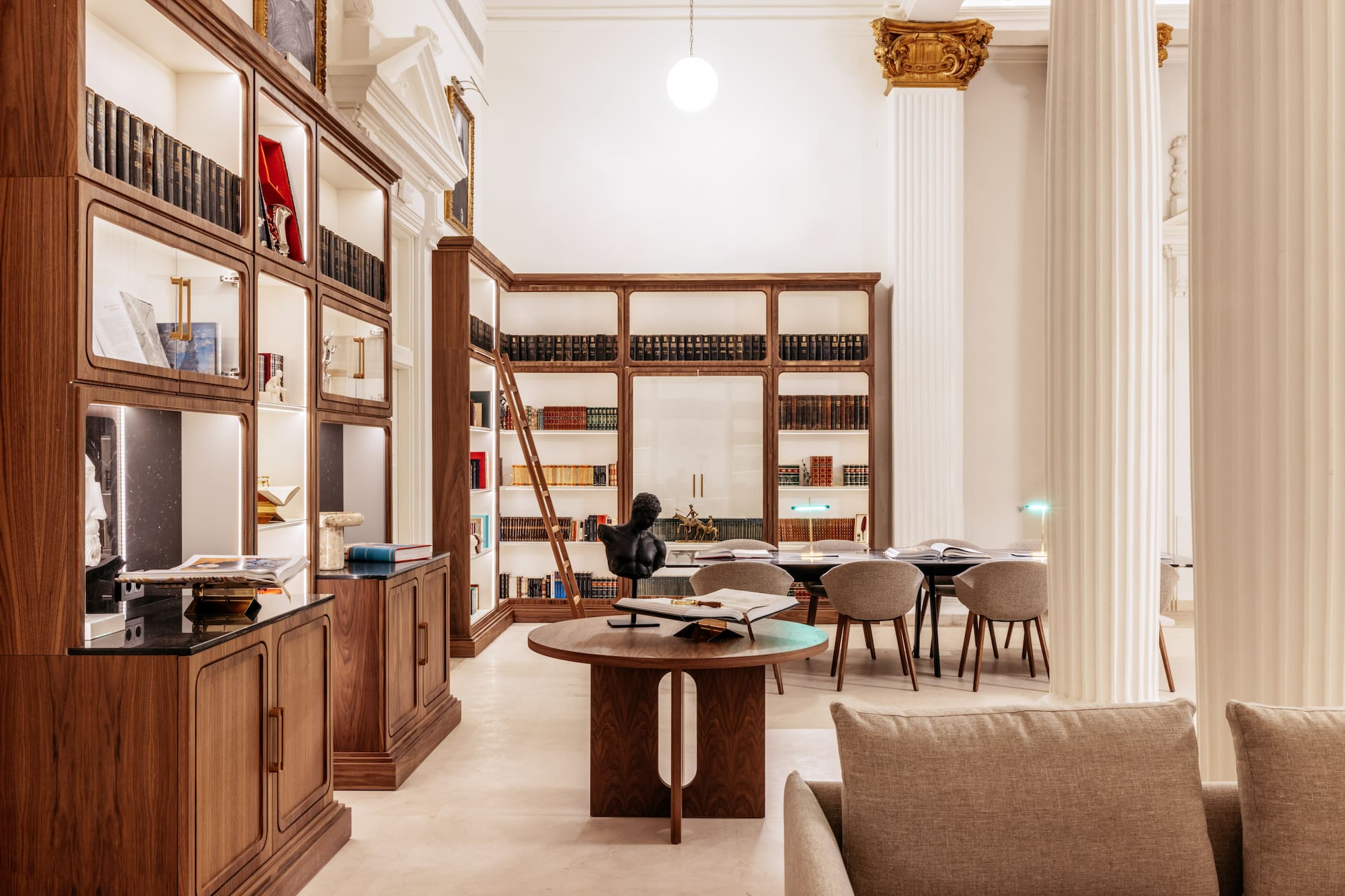 Classical library interior with illuminated wood bookshelves and study area.
