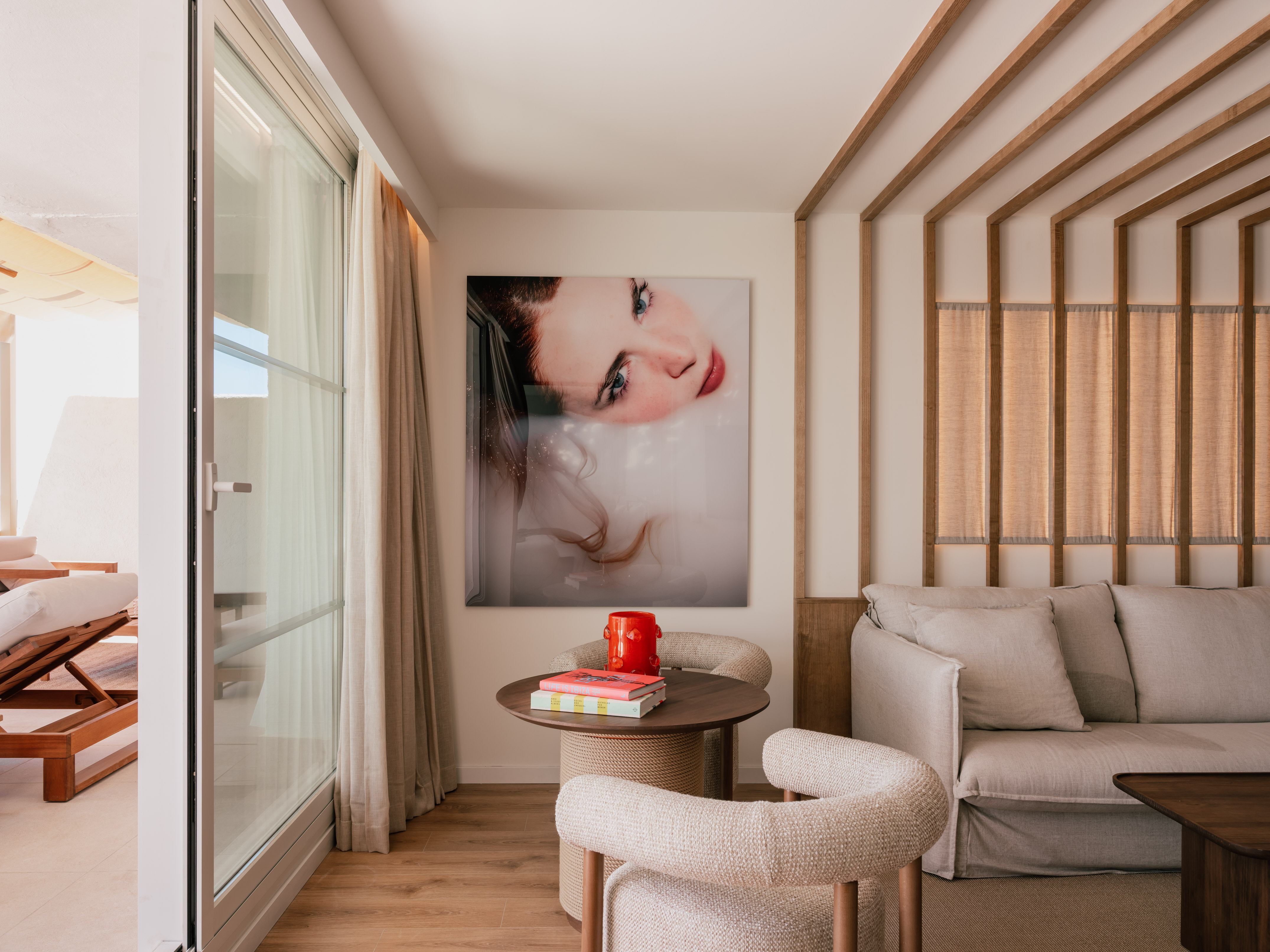 Modern hotel suite with large art, sofa, wooden decor, and terrace access.