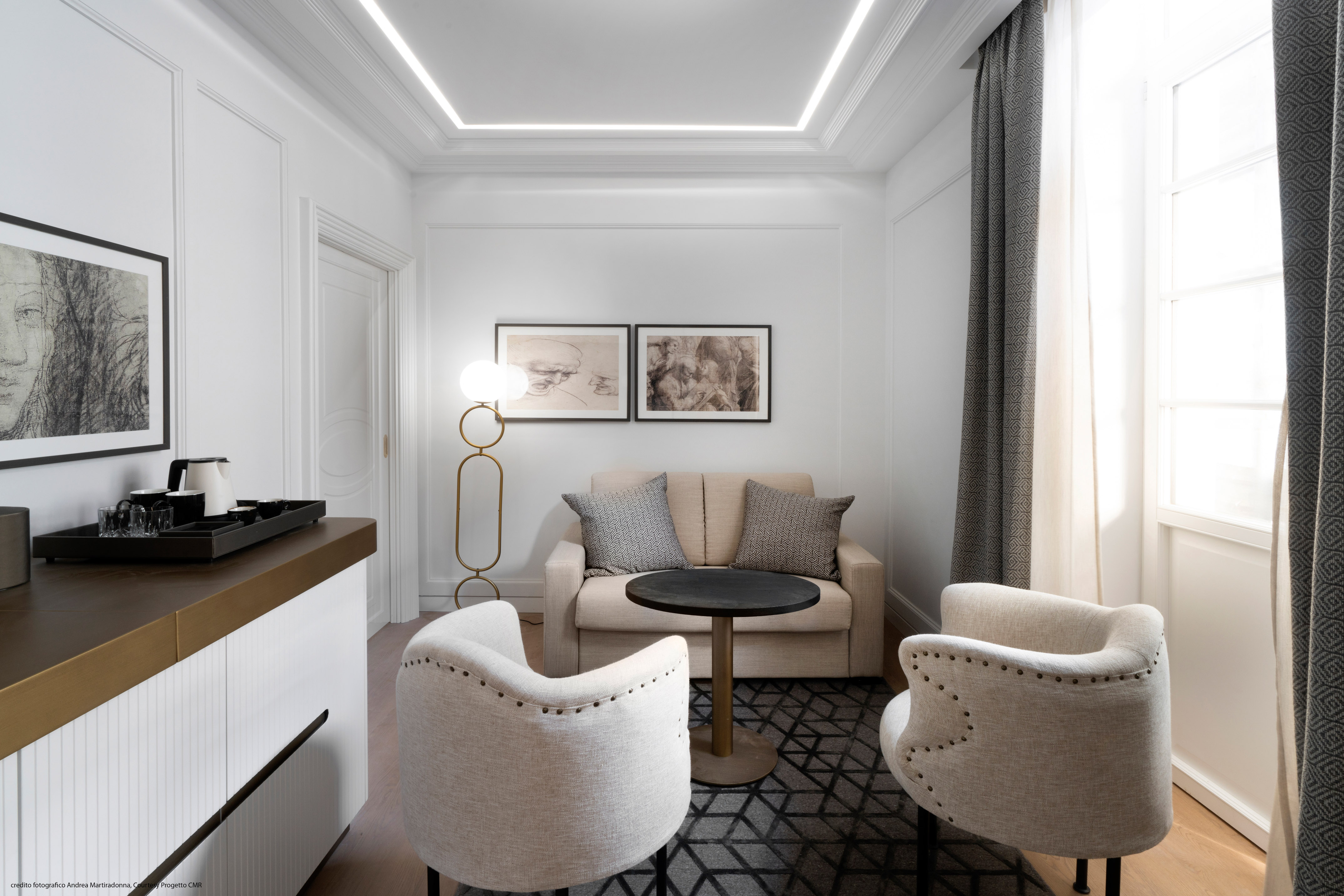 Modern hotel suite living area with neutral sofa, armchairs, and art.