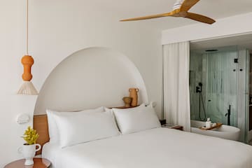 a bed with white sheets and a ceiling fan