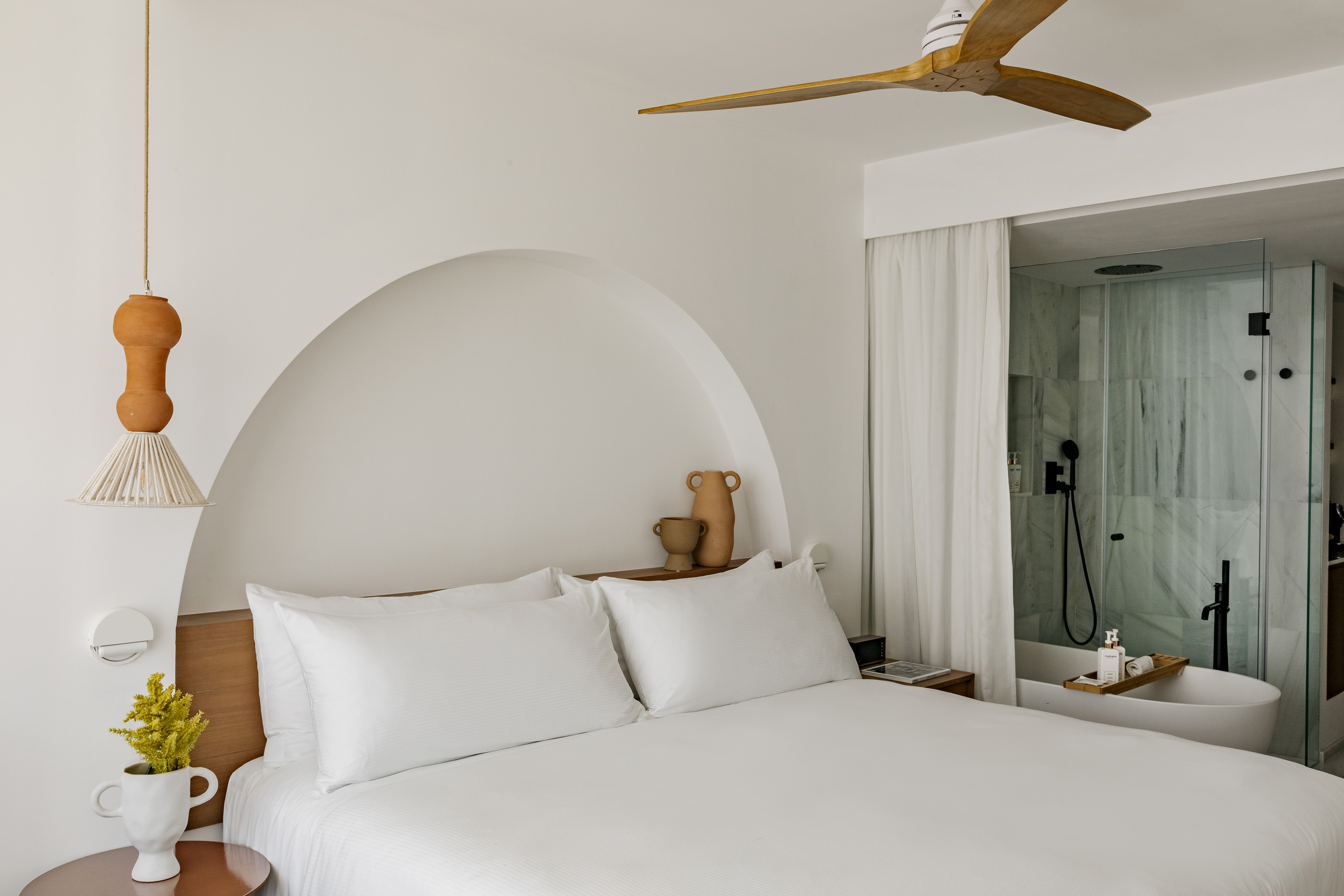 a bed with white sheets and a ceiling fan