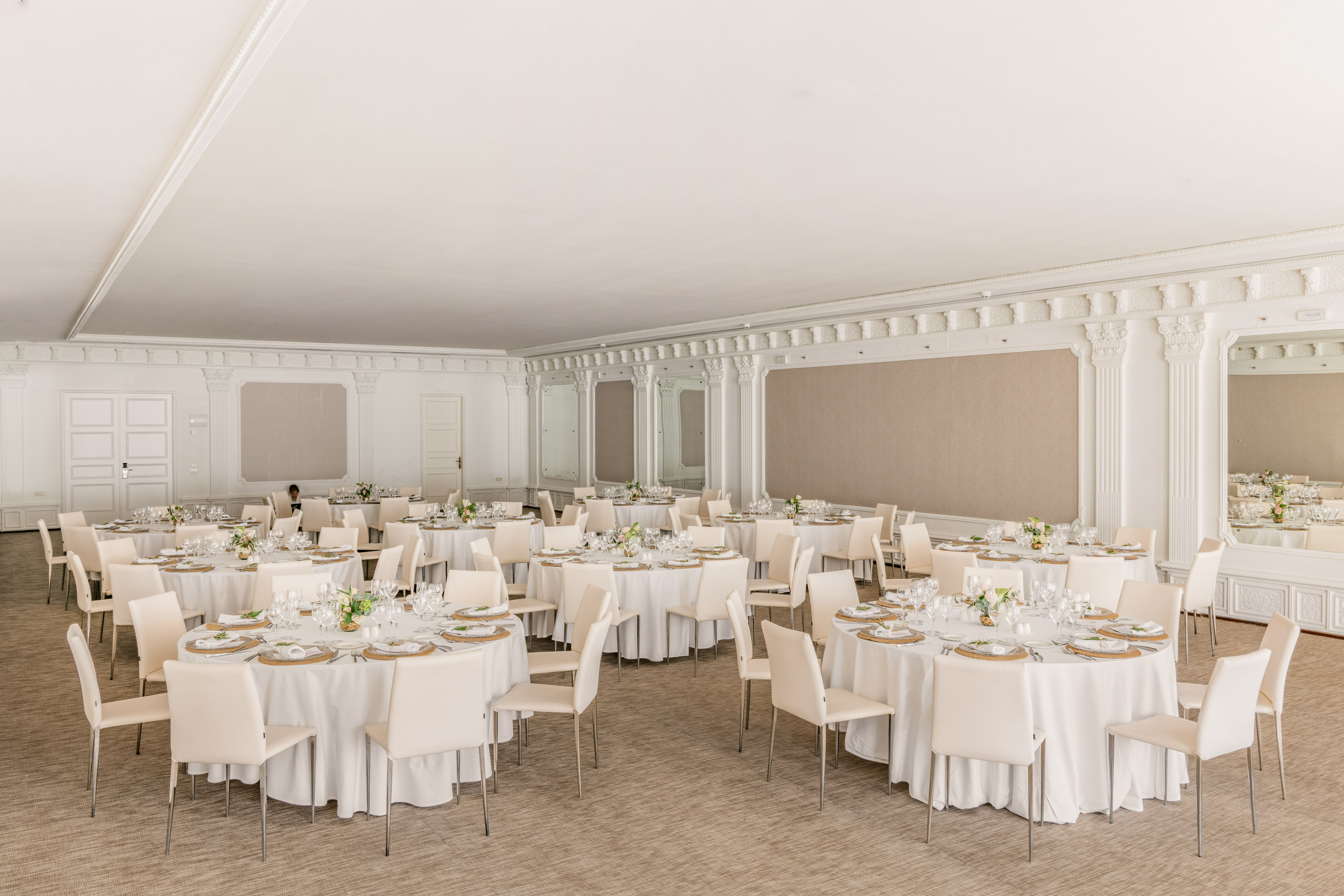 Elegant event hall with round tables, white chairs, and settings.