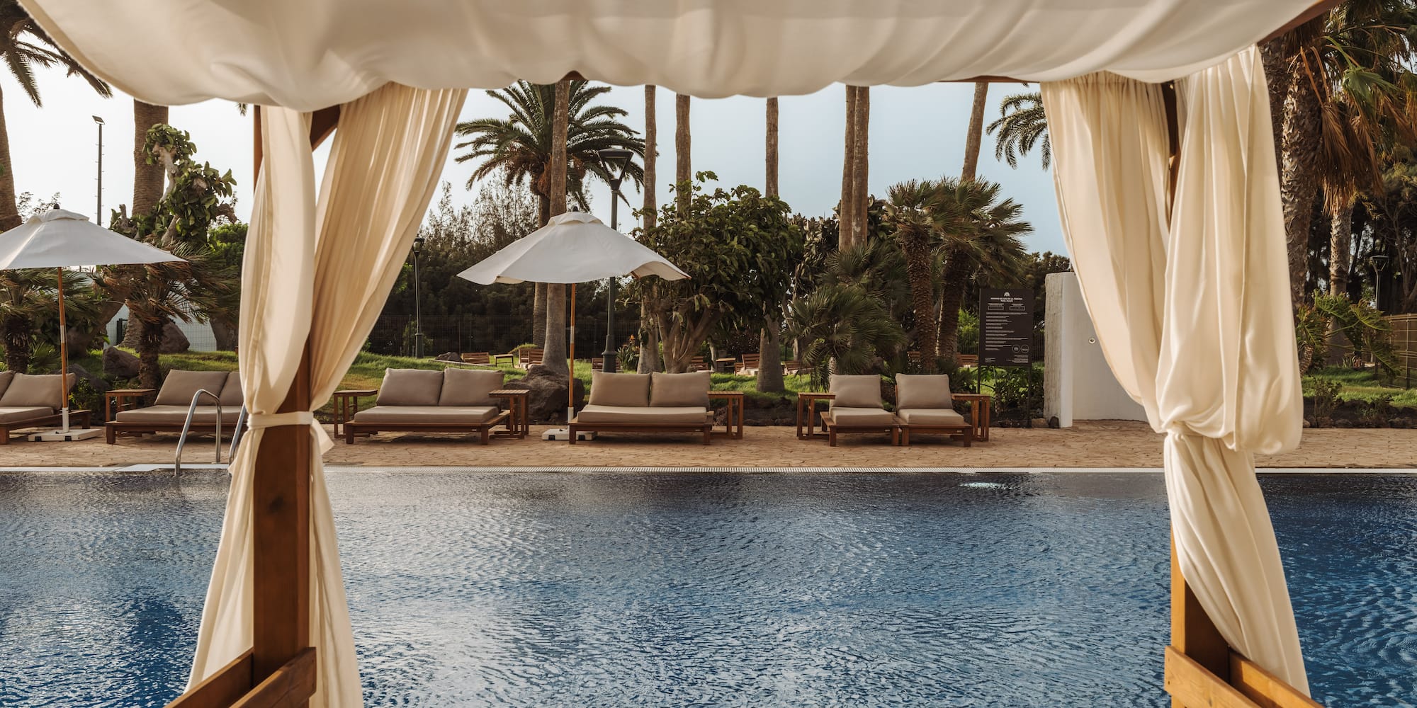 a pool with a white canopy and chairs
