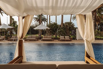 a pool with a white canopy and chairs