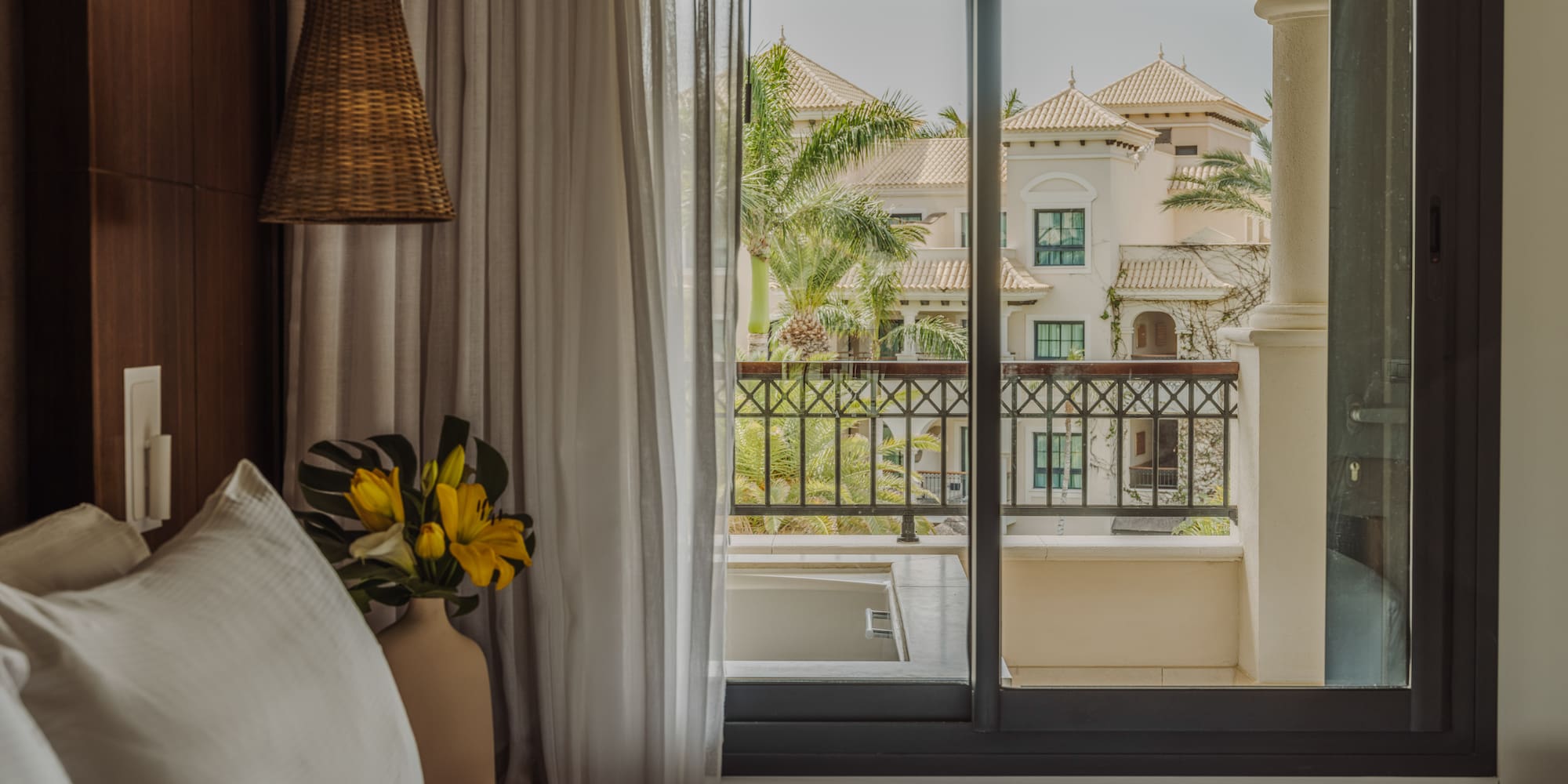 a bed with a vase of flowers and a window