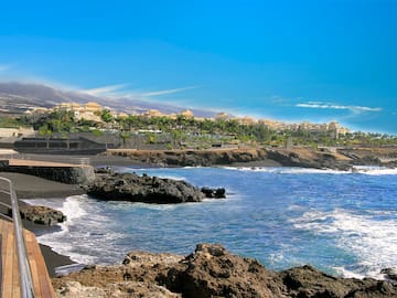 a rocky beach with buildings and a body of water