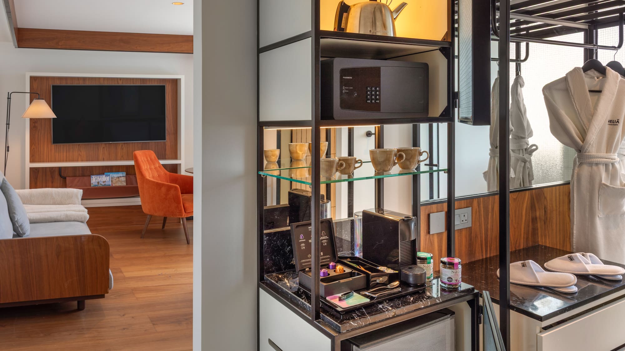 Modern hotel room with Nespresso mini-bar, safe, kettle, bathrobes, and TV lounge.