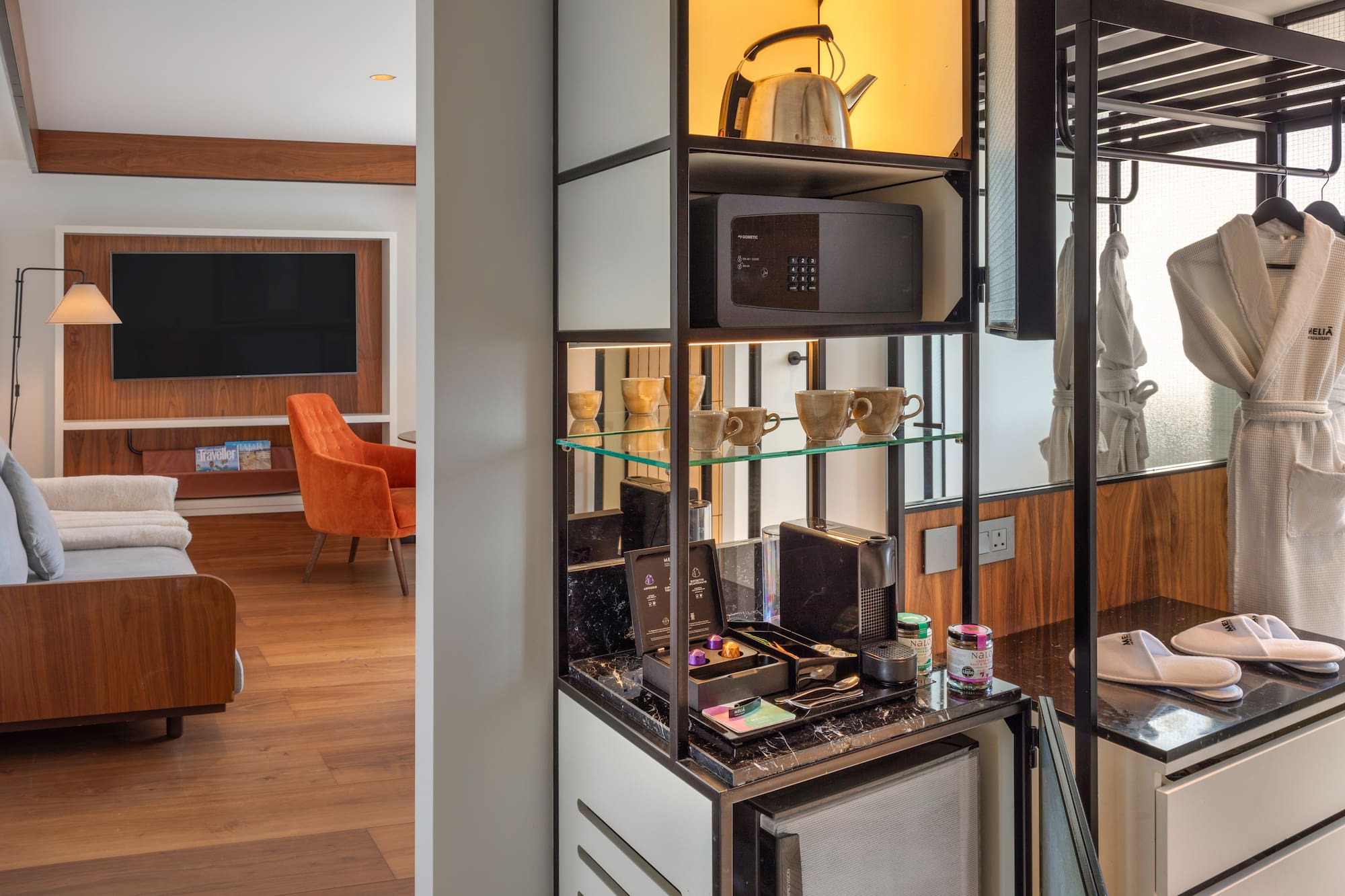 Modern hotel room with Nespresso station, mini-fridge, safe, and bathrobes.