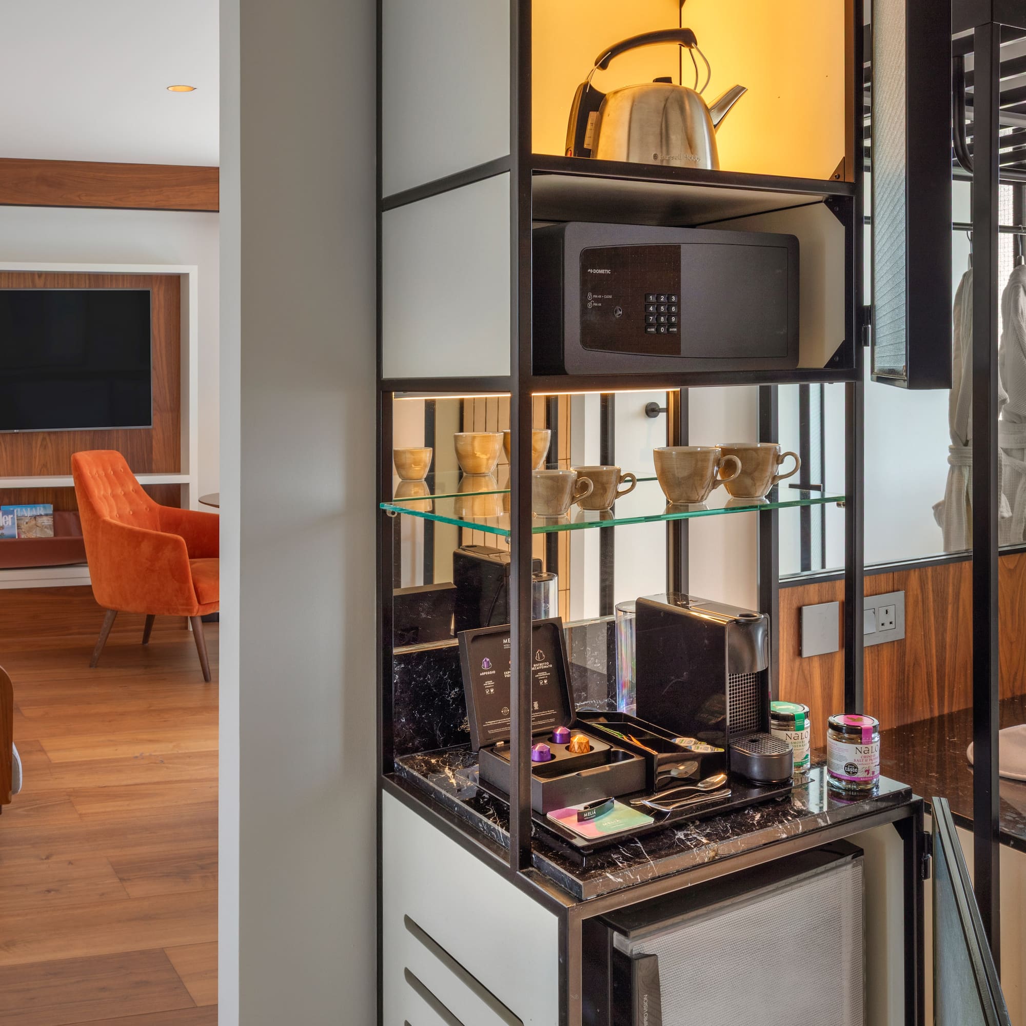 Modern hotel room with Nespresso mini-bar, safe, kettle, bathrobes, and TV lounge.