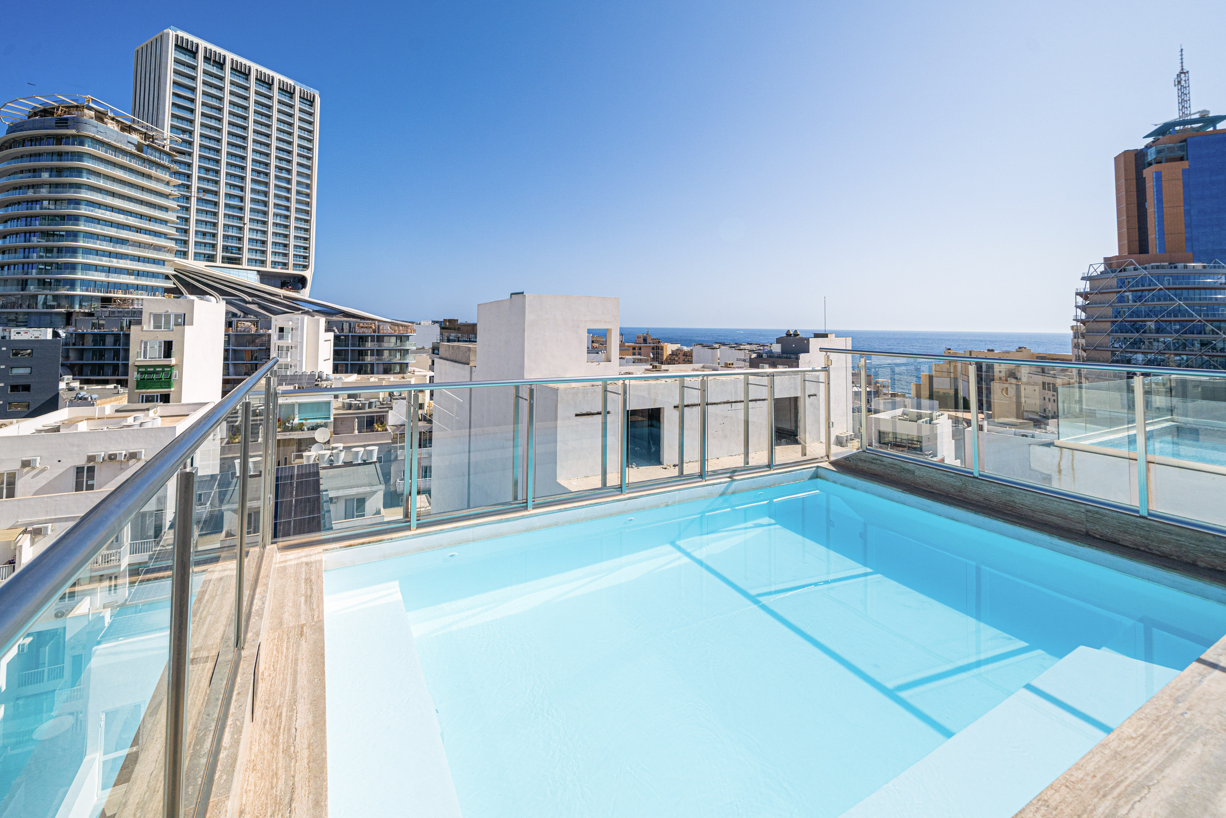 Modern rooftop pool with panoramic city skyline and ocean views.