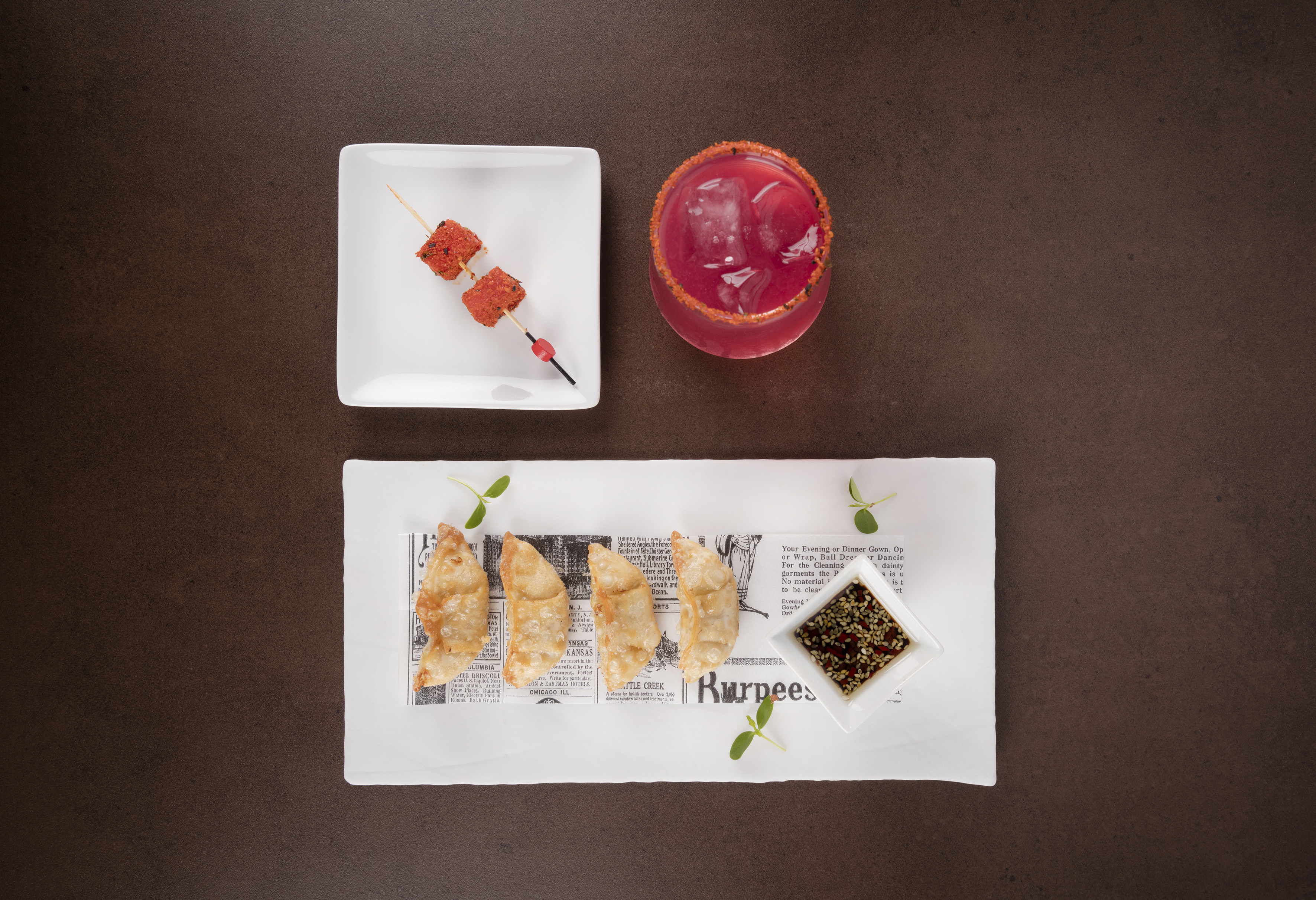 Crispy fried dumplings, red cocktail, and seasoned appetizer skewers.
