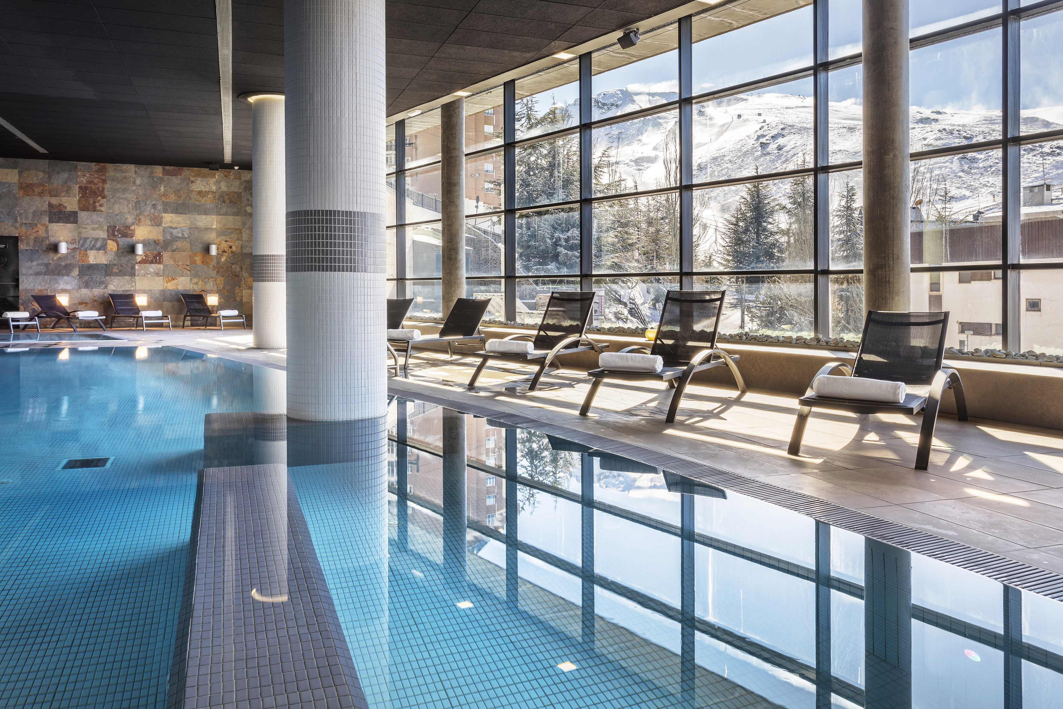 Indoor swimming pool with snowy mountain views at a modern ski resort.