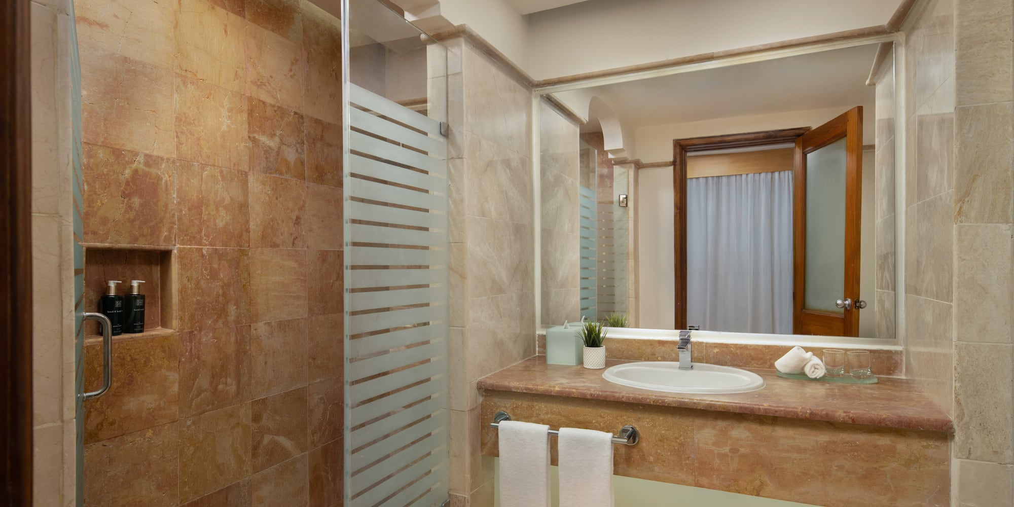 Luxury hotel bathroom with marble shower, modern vanity, and fresh towels.
