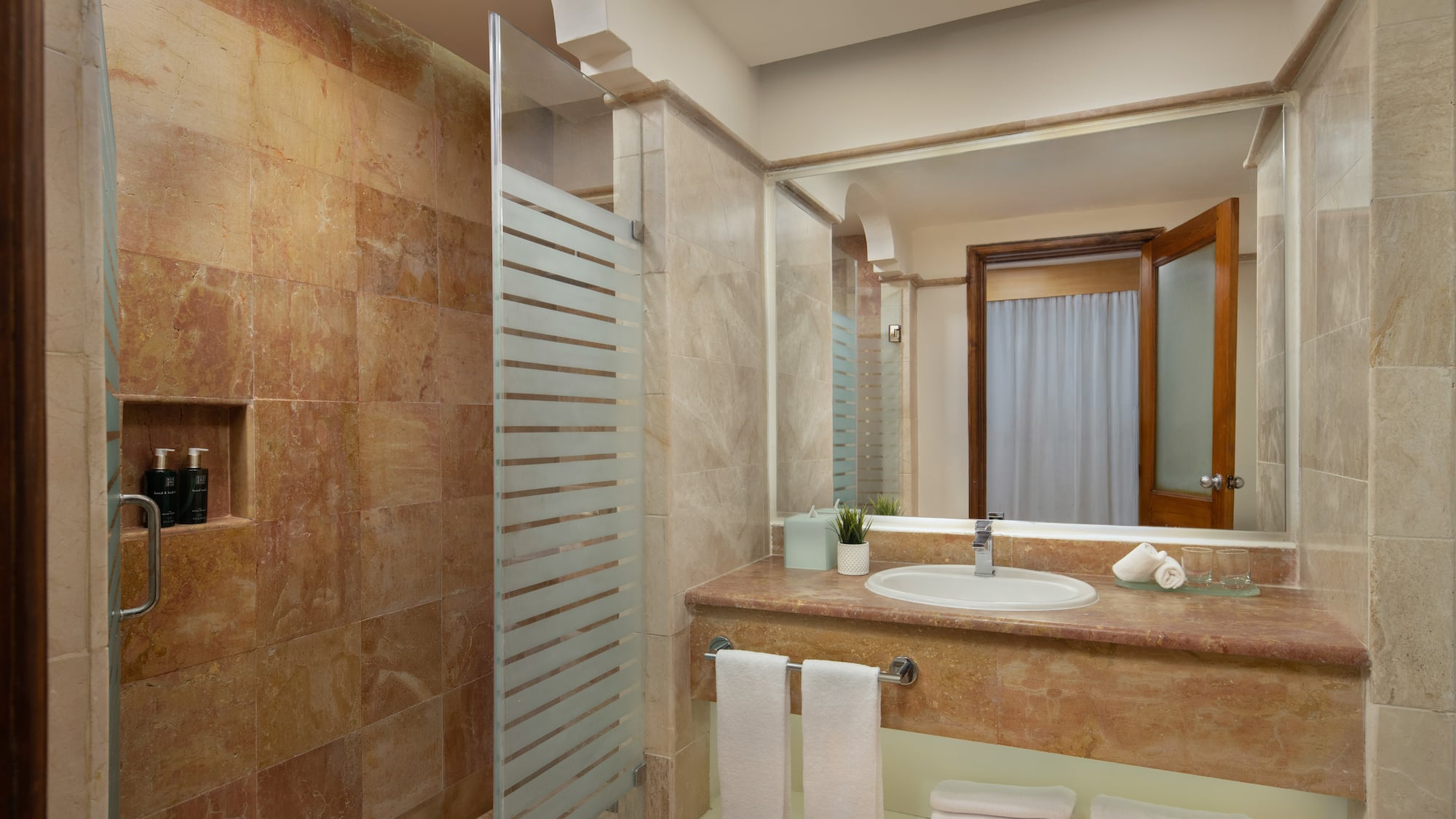 Luxury hotel bathroom with marble shower, modern vanity, and fresh towels.