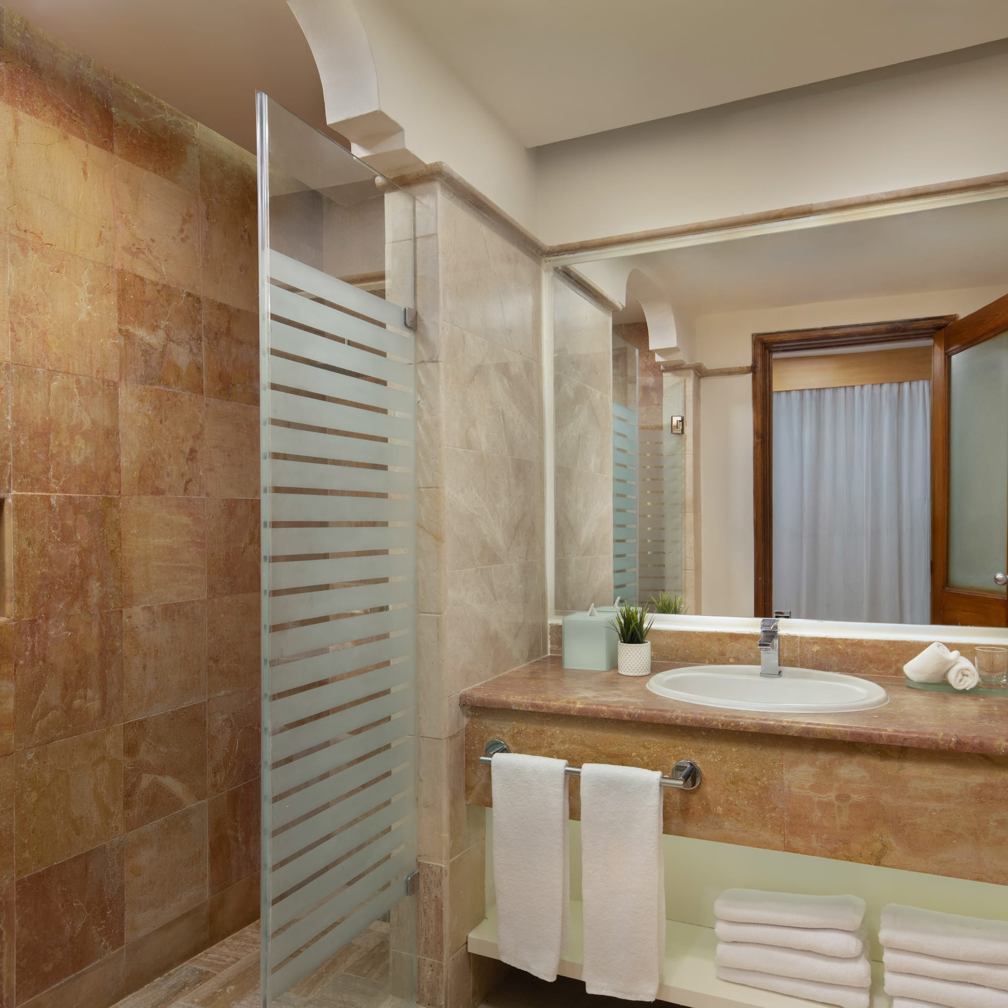 Luxury hotel bathroom with marble shower, modern vanity, and fresh towels.