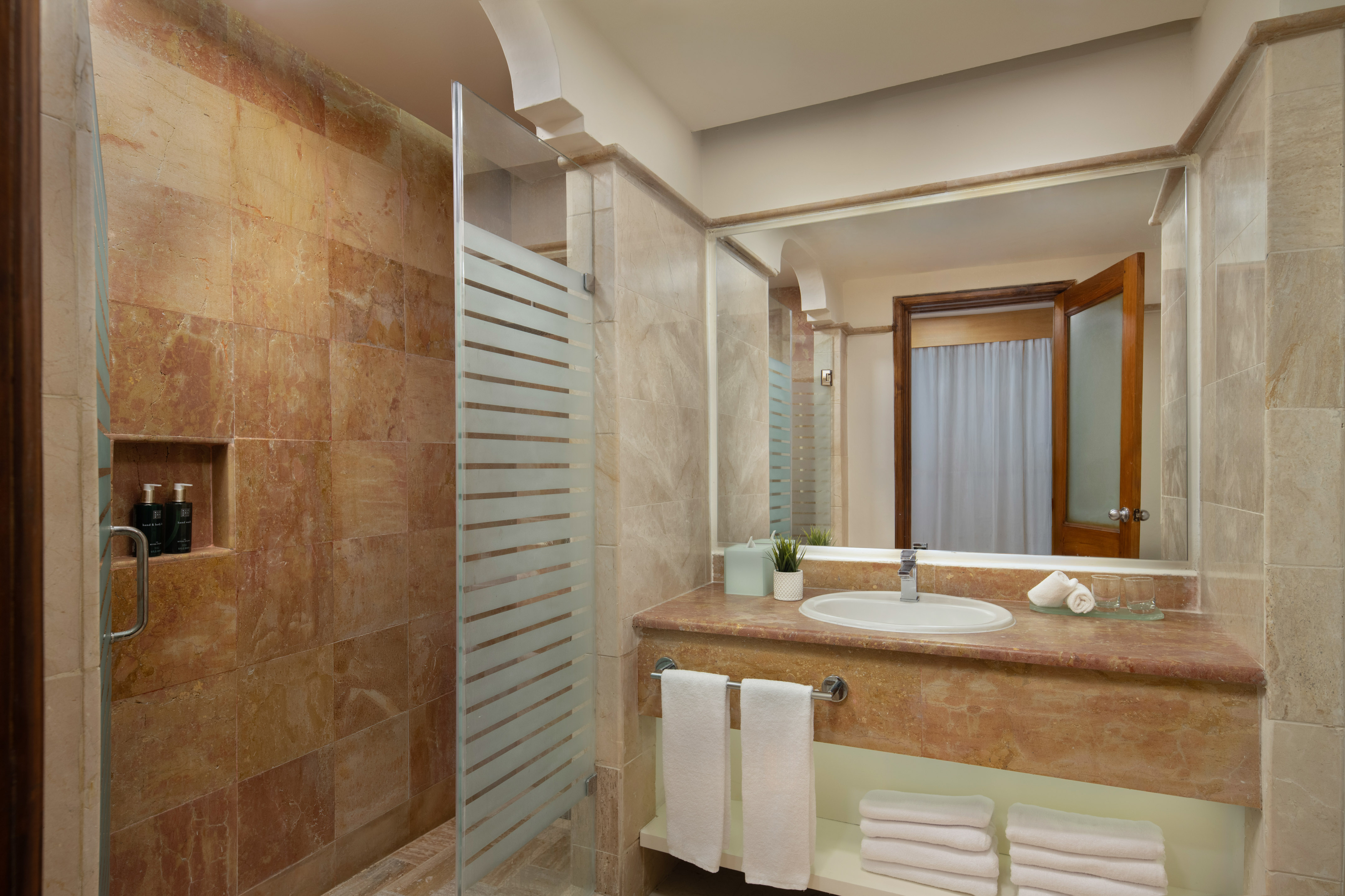 Luxury hotel bathroom with marble shower, modern vanity, and fresh towels.