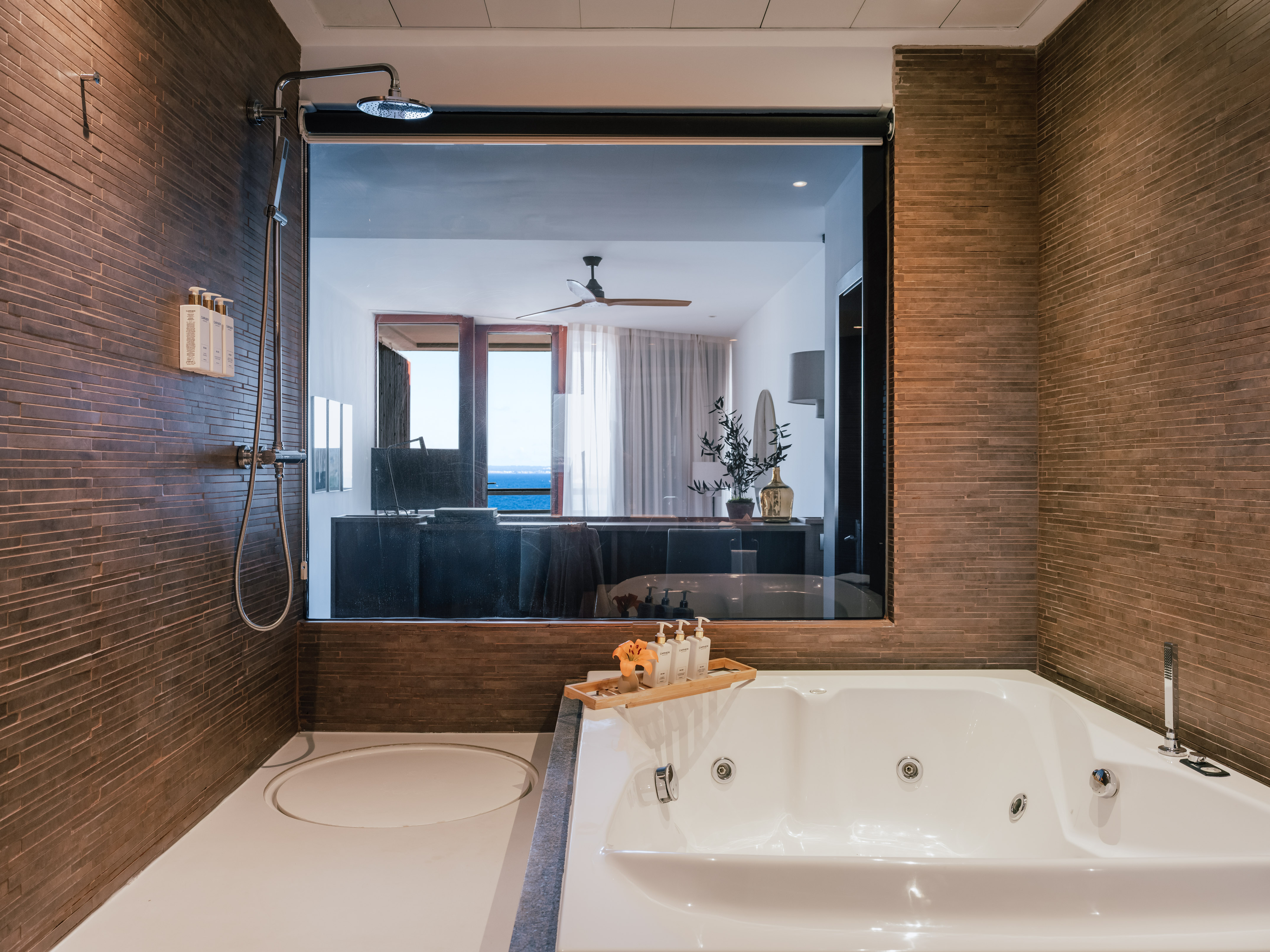 Luxury hotel bathroom with shower, jetted tub, and ocean view.