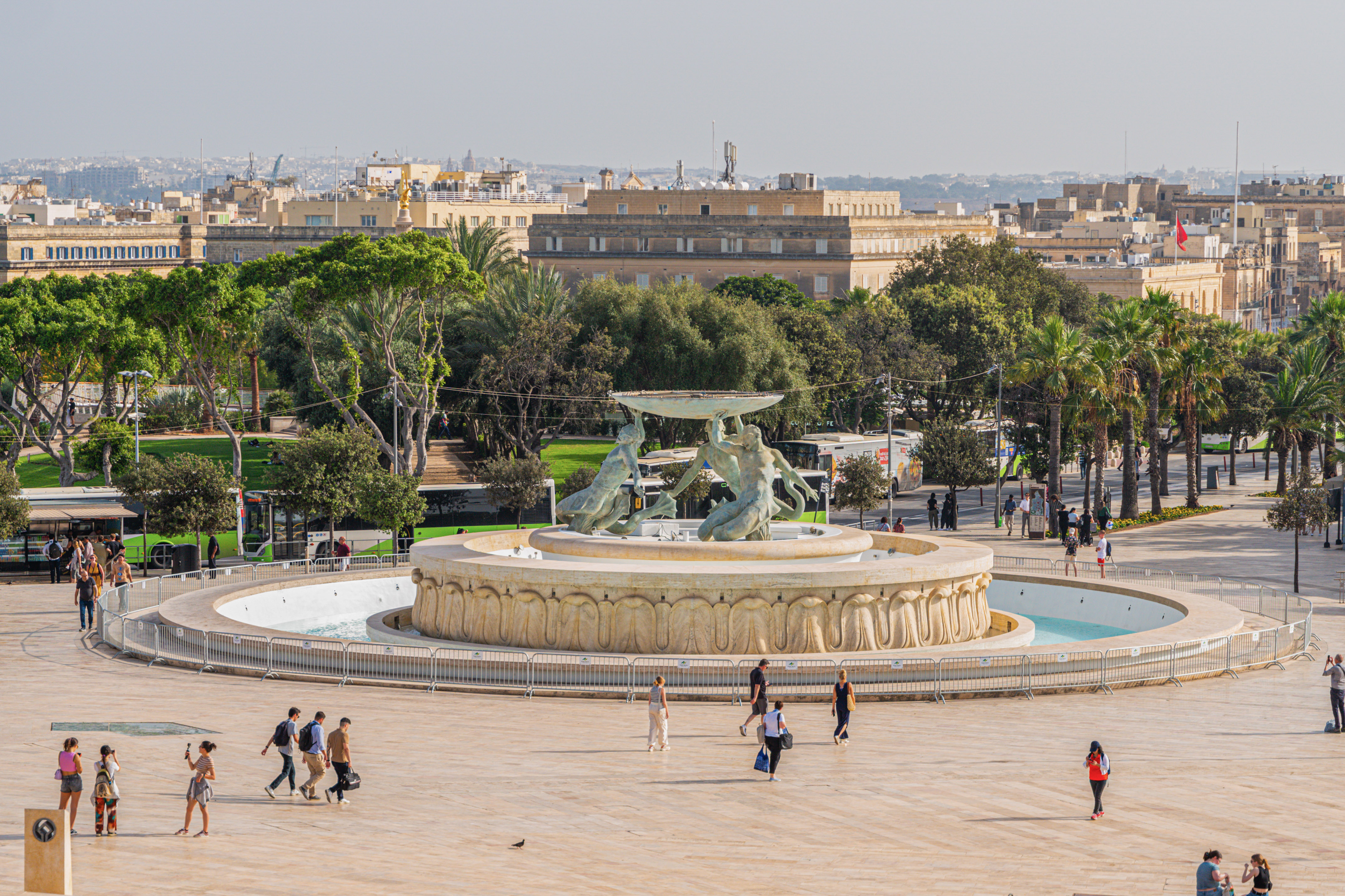 Valletta's Triton Fountain in Malta, public square, people, city skyline.