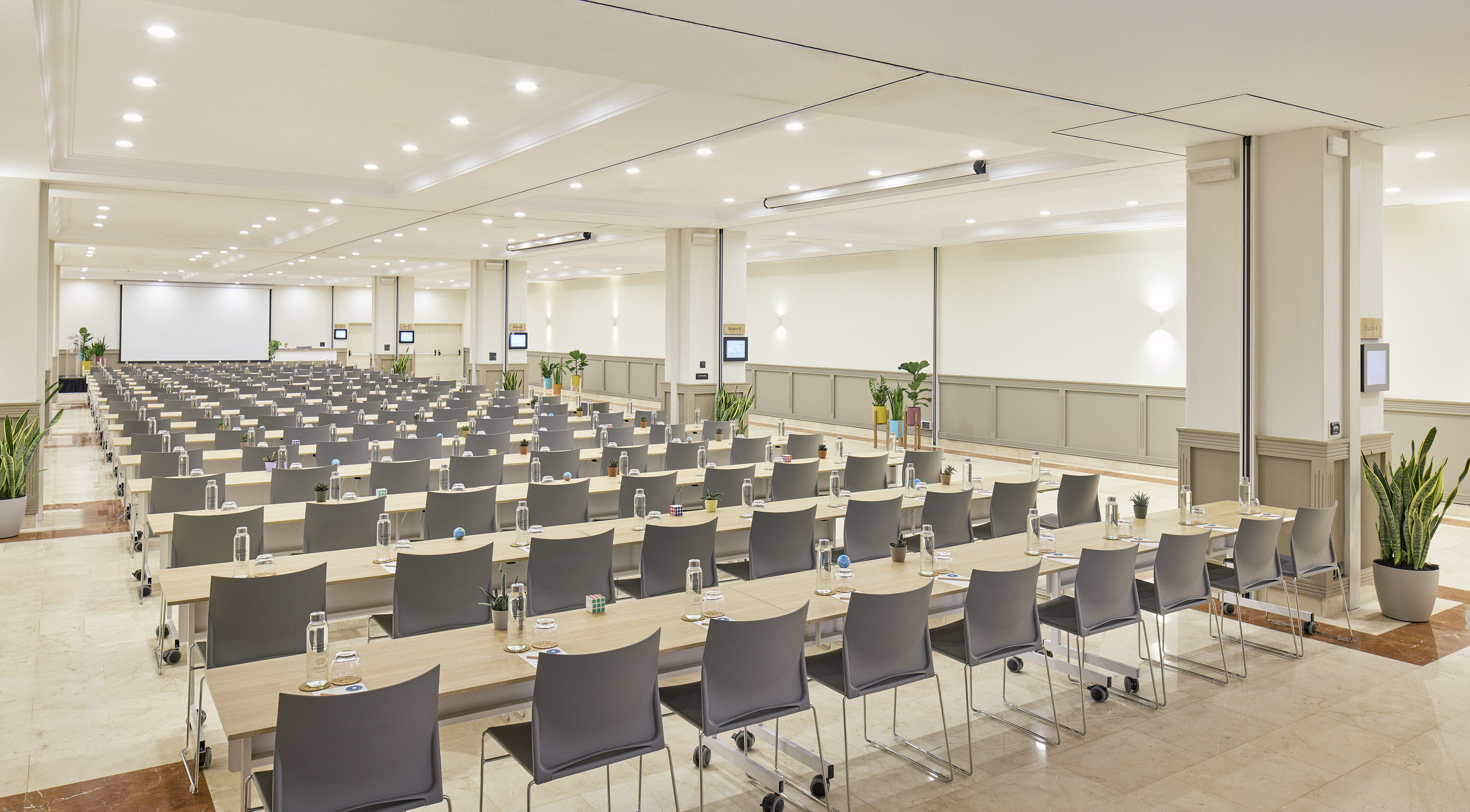 Large conference hall with tables, chairs, and a projection screen for events.