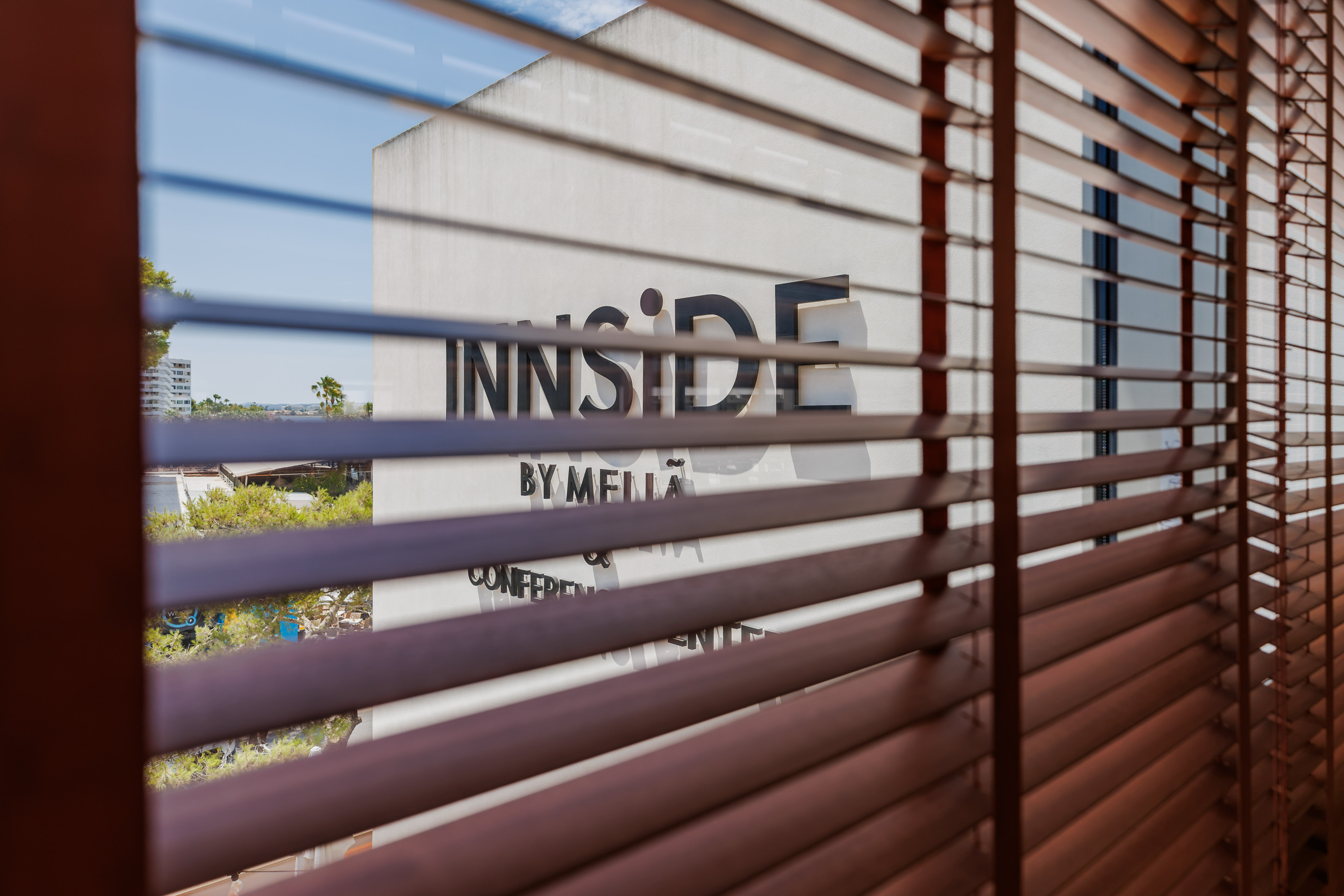 View of INNSIDE by Melia hotel sign through wooden Venetian blinds.