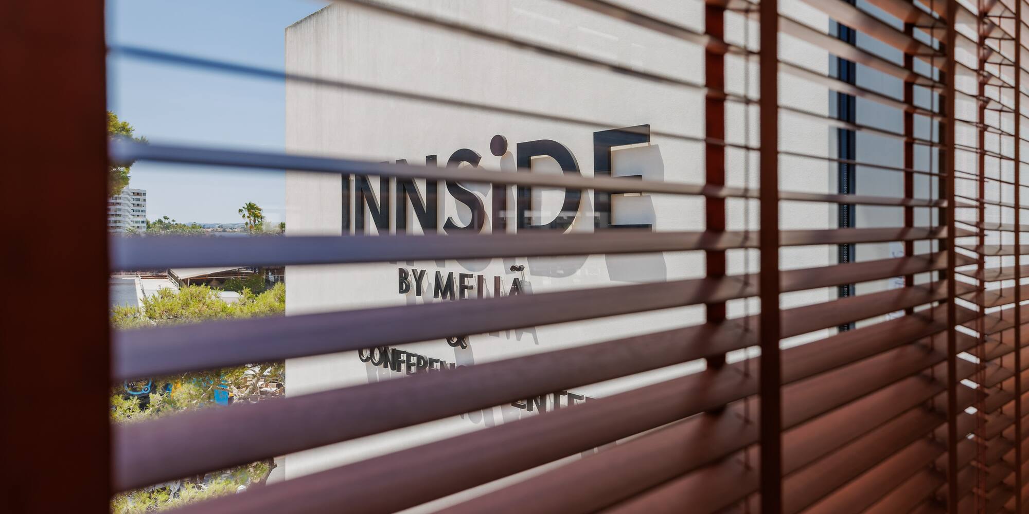 View of INNSIDE by Melia hotel sign through wooden Venetian blinds.