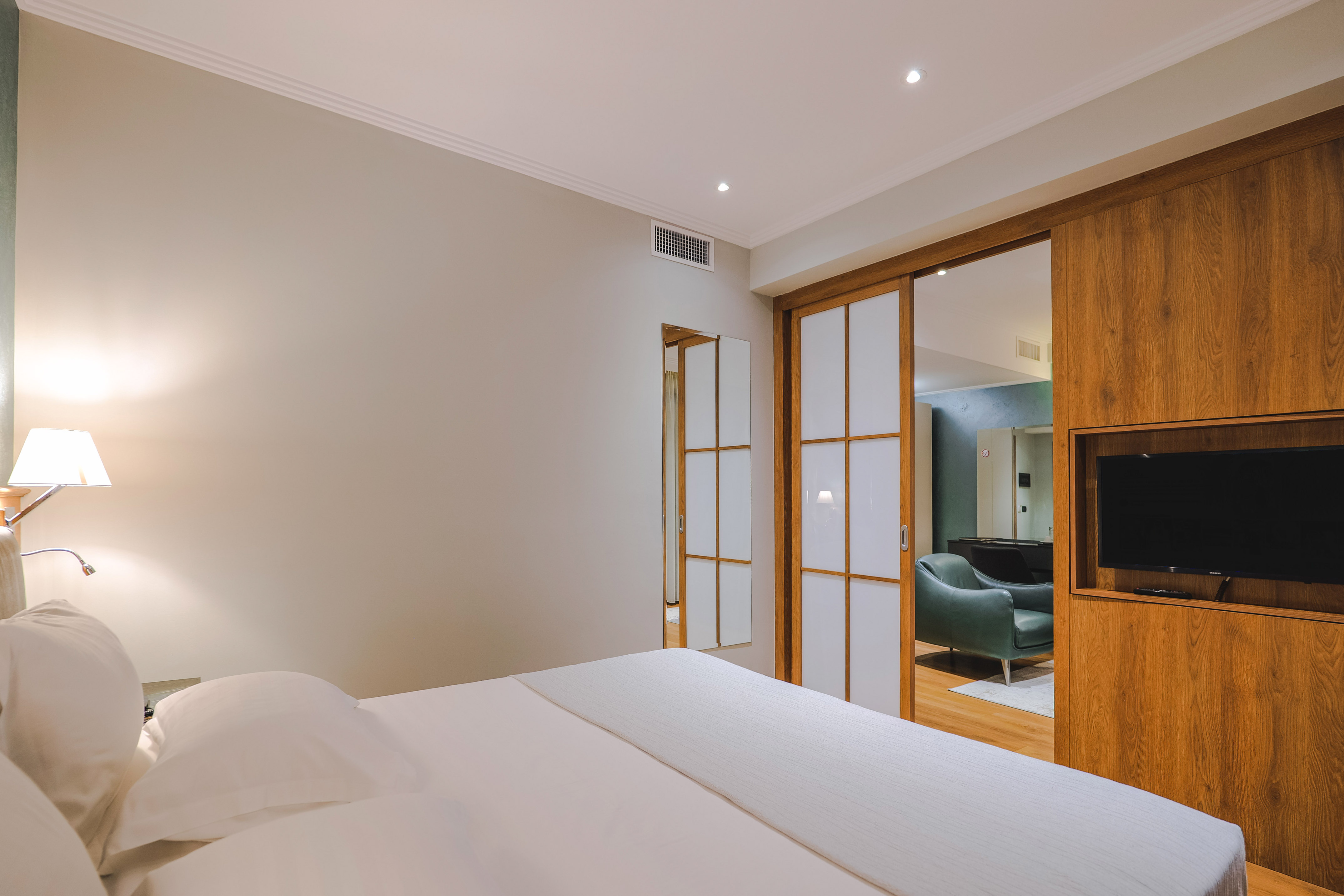 a bed with white sheets and a lamp in a room