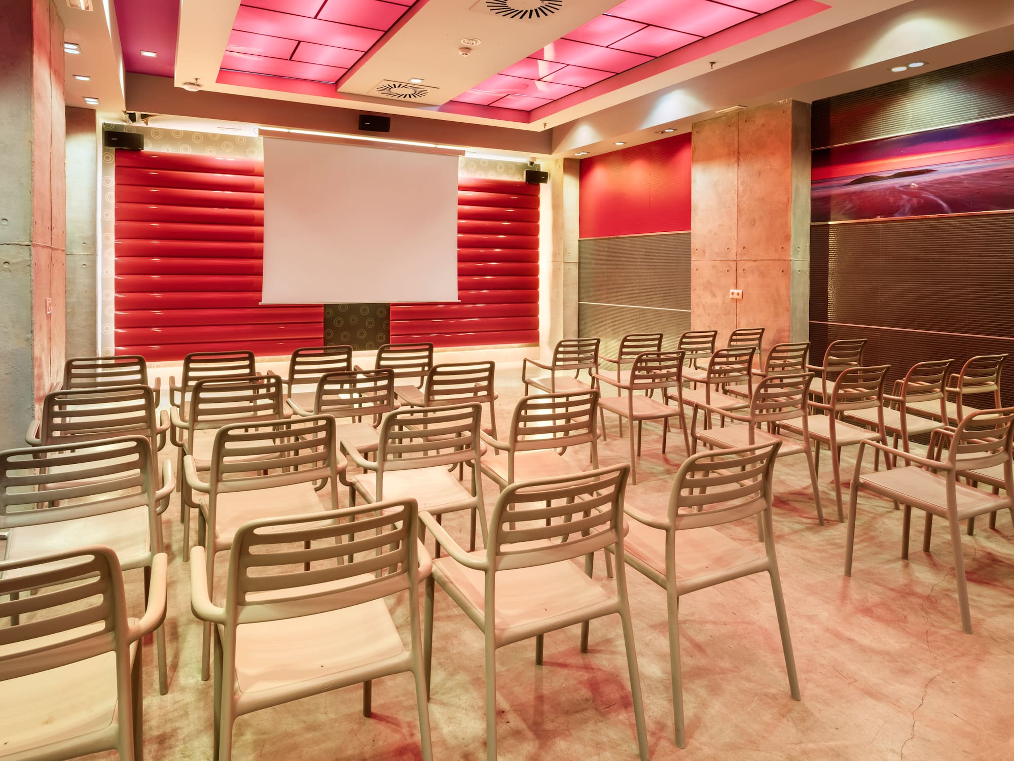 Empty modern conference room with red decor, seating, and projection screen.