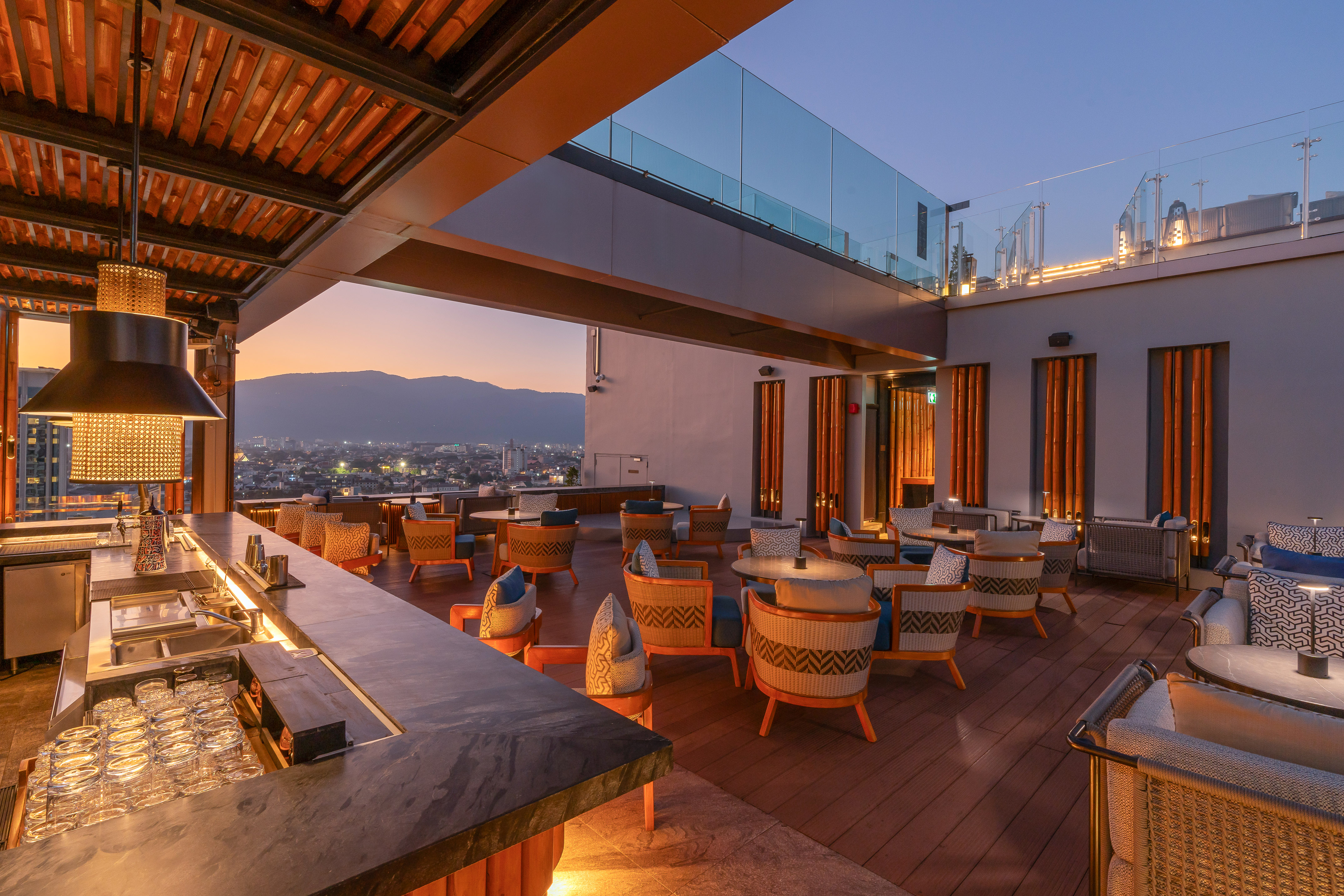 Elegant rooftop bar lounge with city skyline at dusk, stylish furniture.