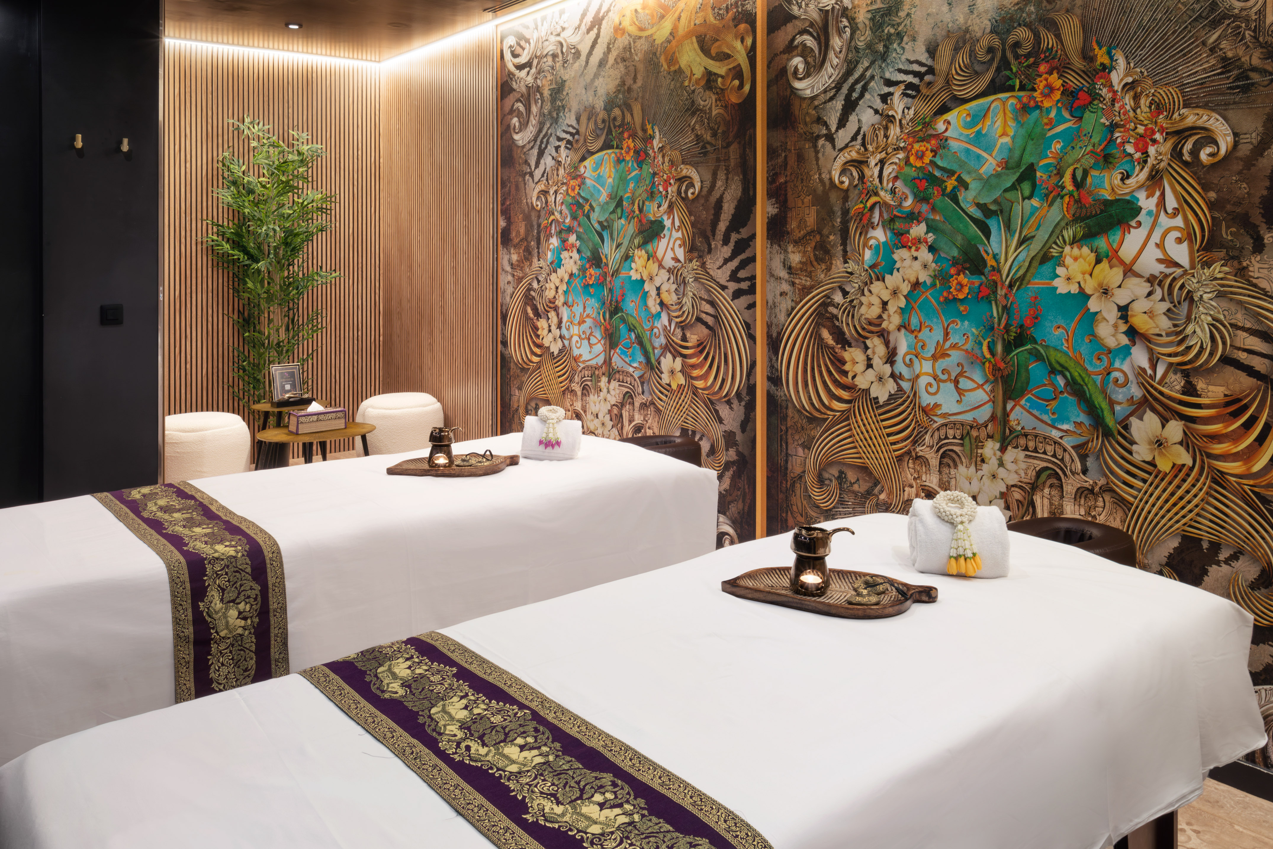 Relaxing spa treatment room with two massage beds and exotic floral wall art.