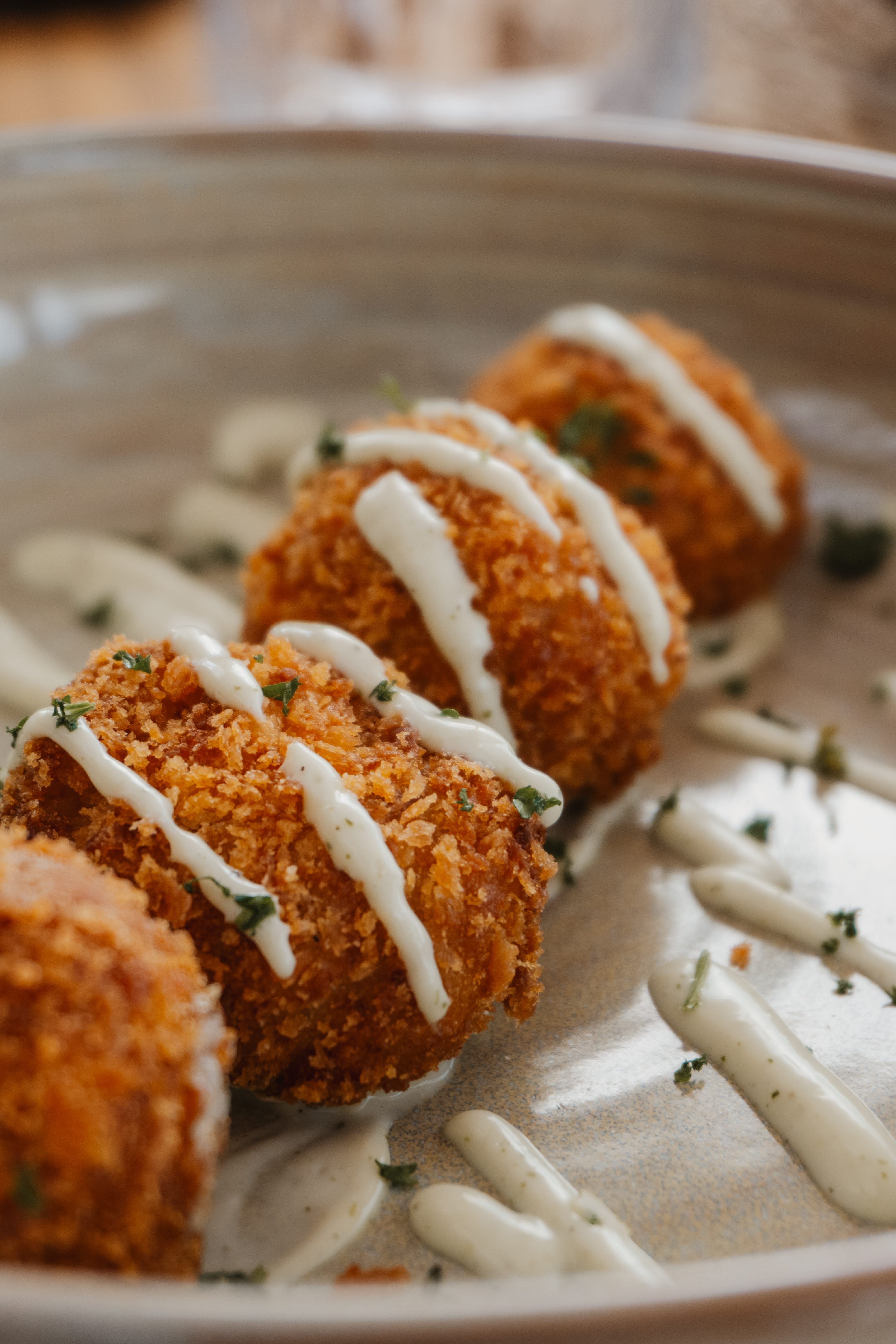 Crispy breaded croquettes topped with creamy sauce and fresh parsley.