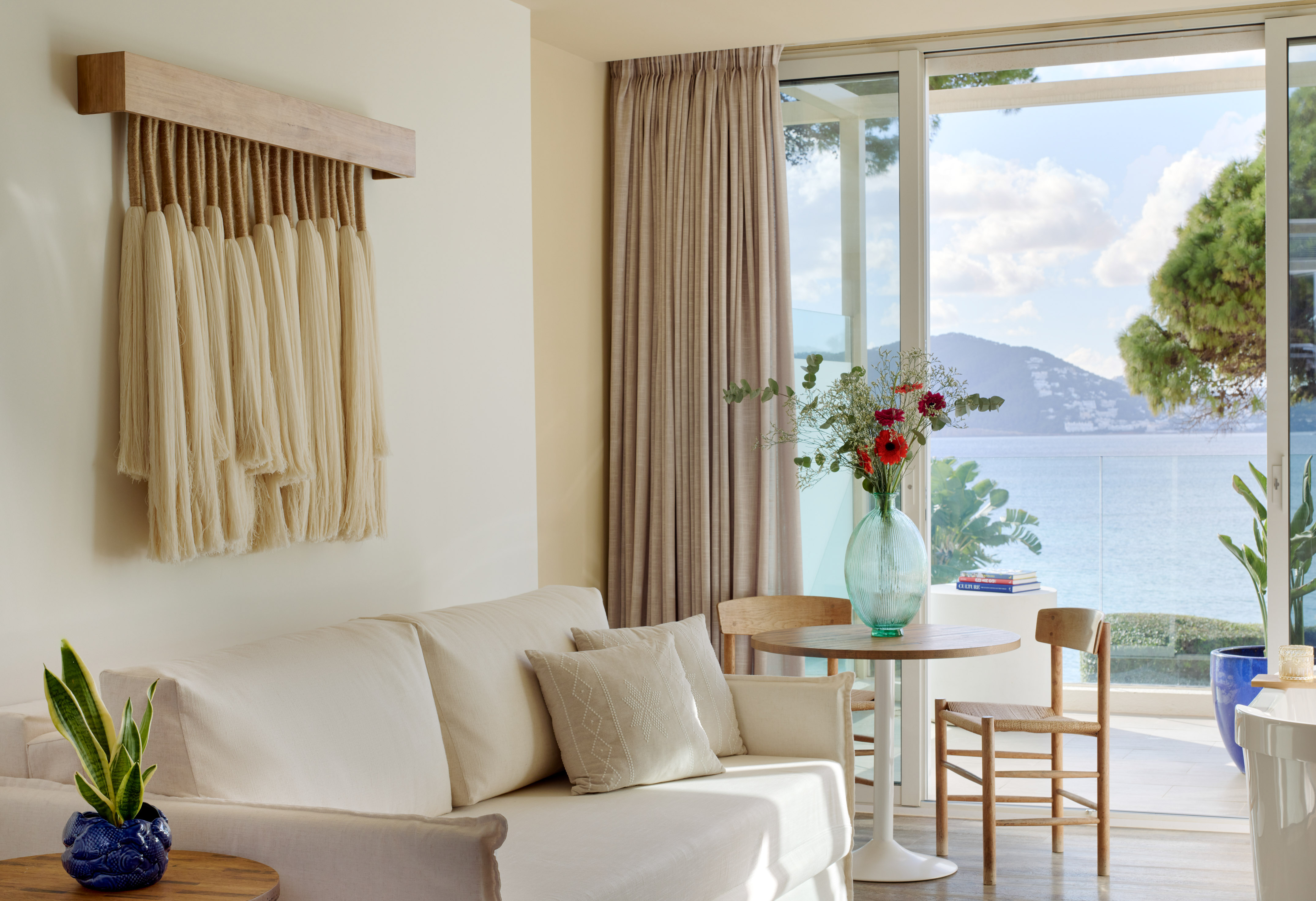 Modern hotel living room with white sofa, coastal decor, and balcony sea view.