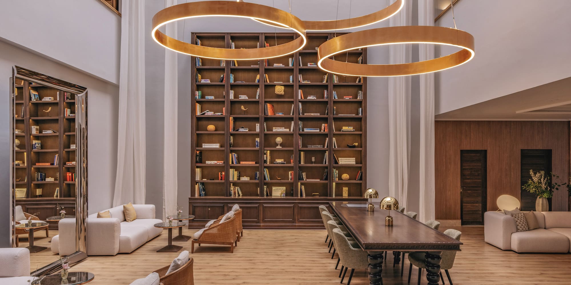 Luxury lounge library with circular chandeliers and extensive bookshelf.