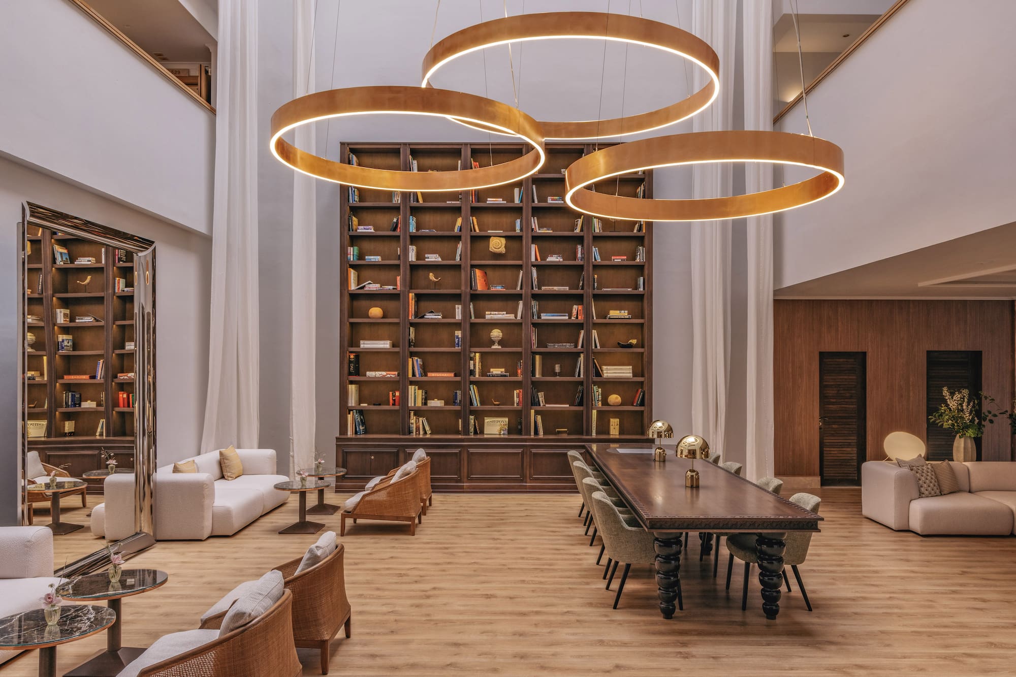 Luxury lounge library with circular chandeliers and extensive bookshelf.